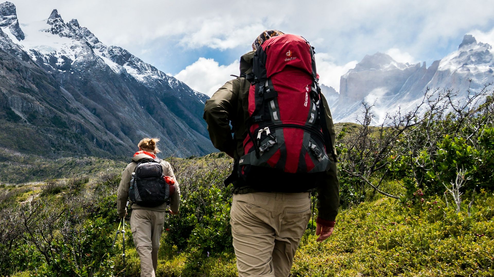 two person walking towards mountain covered with snow