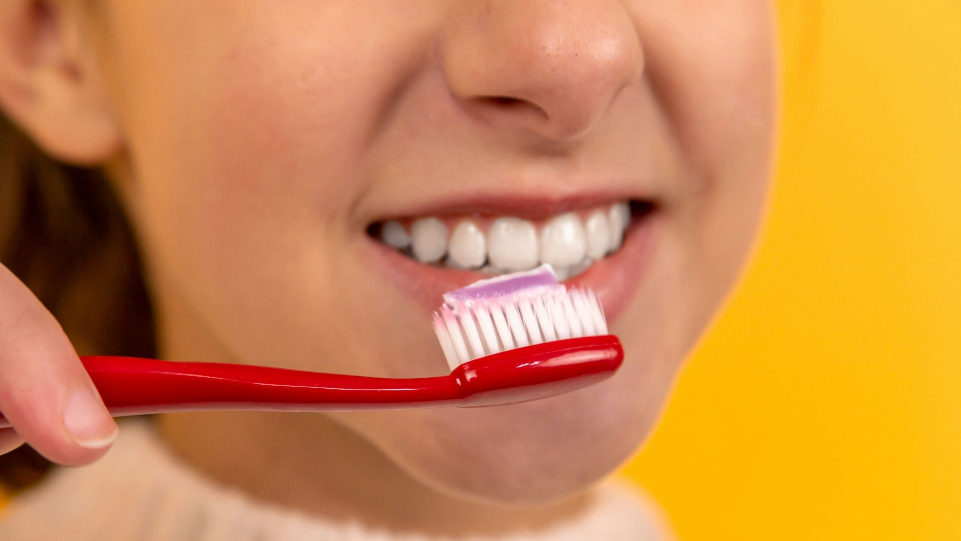 girl with red and white toothbrush in mouth