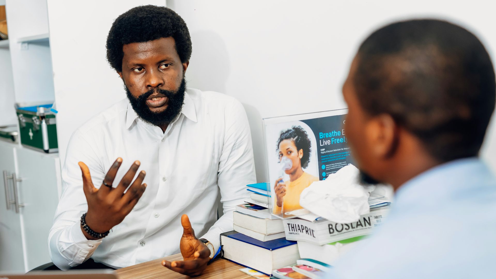 A man sitting at a desk talking to another man