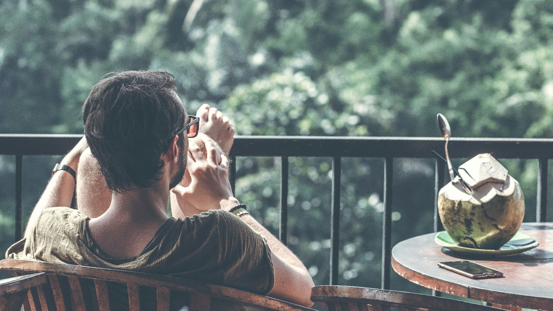 man sitting on armchair near table with opened coconut