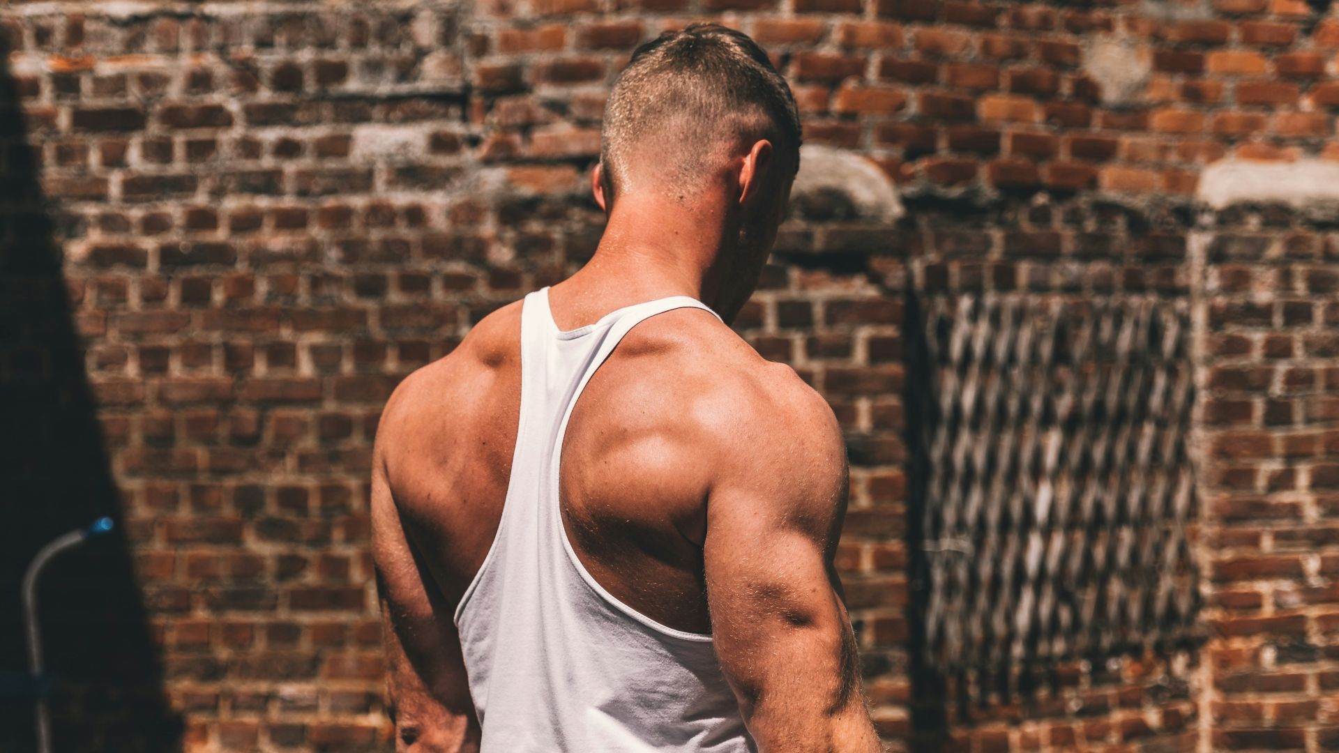man in white tank top and black and white shorts sitting on black wheel chair