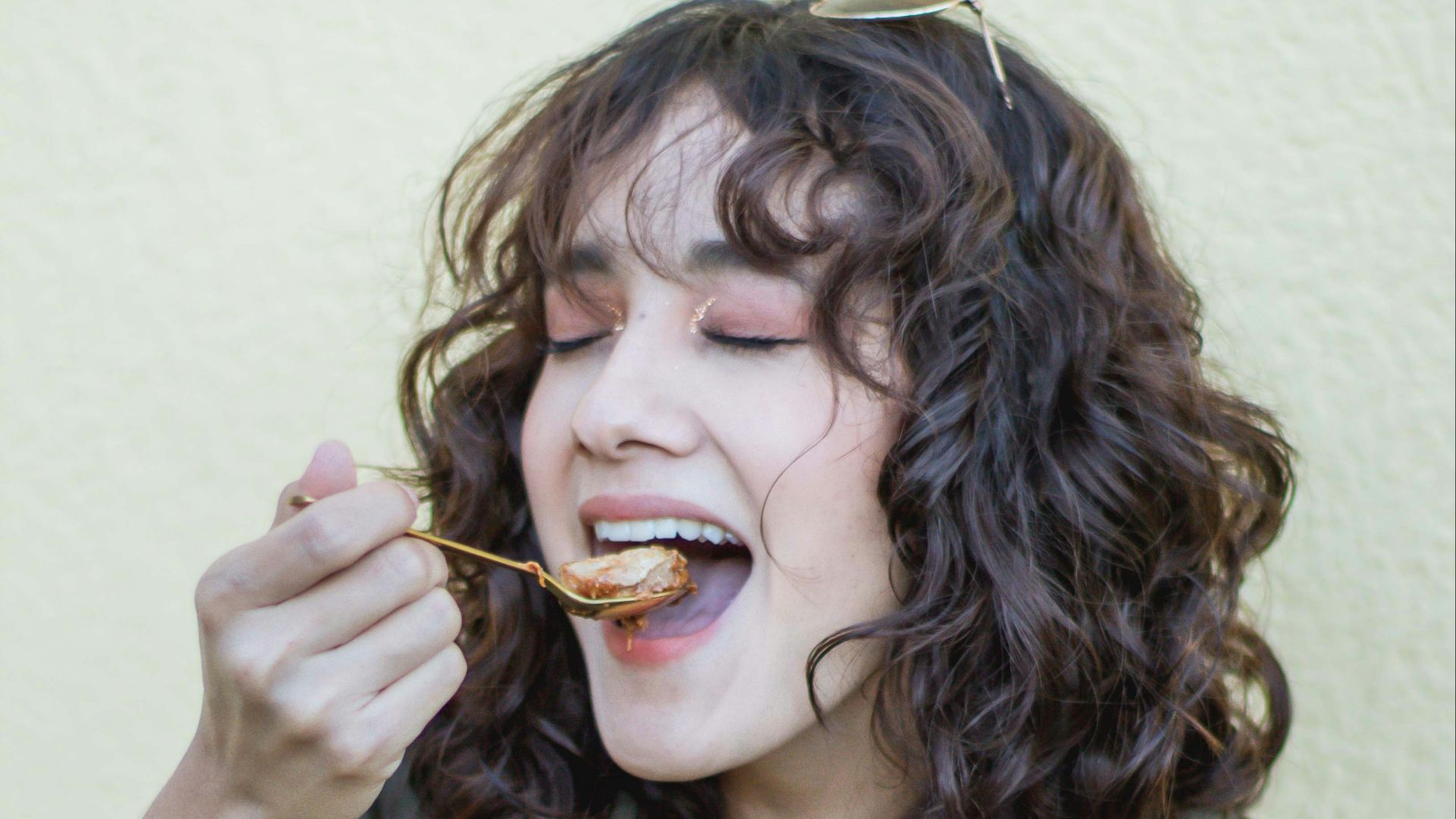 a woman eating food out of a pink bowl