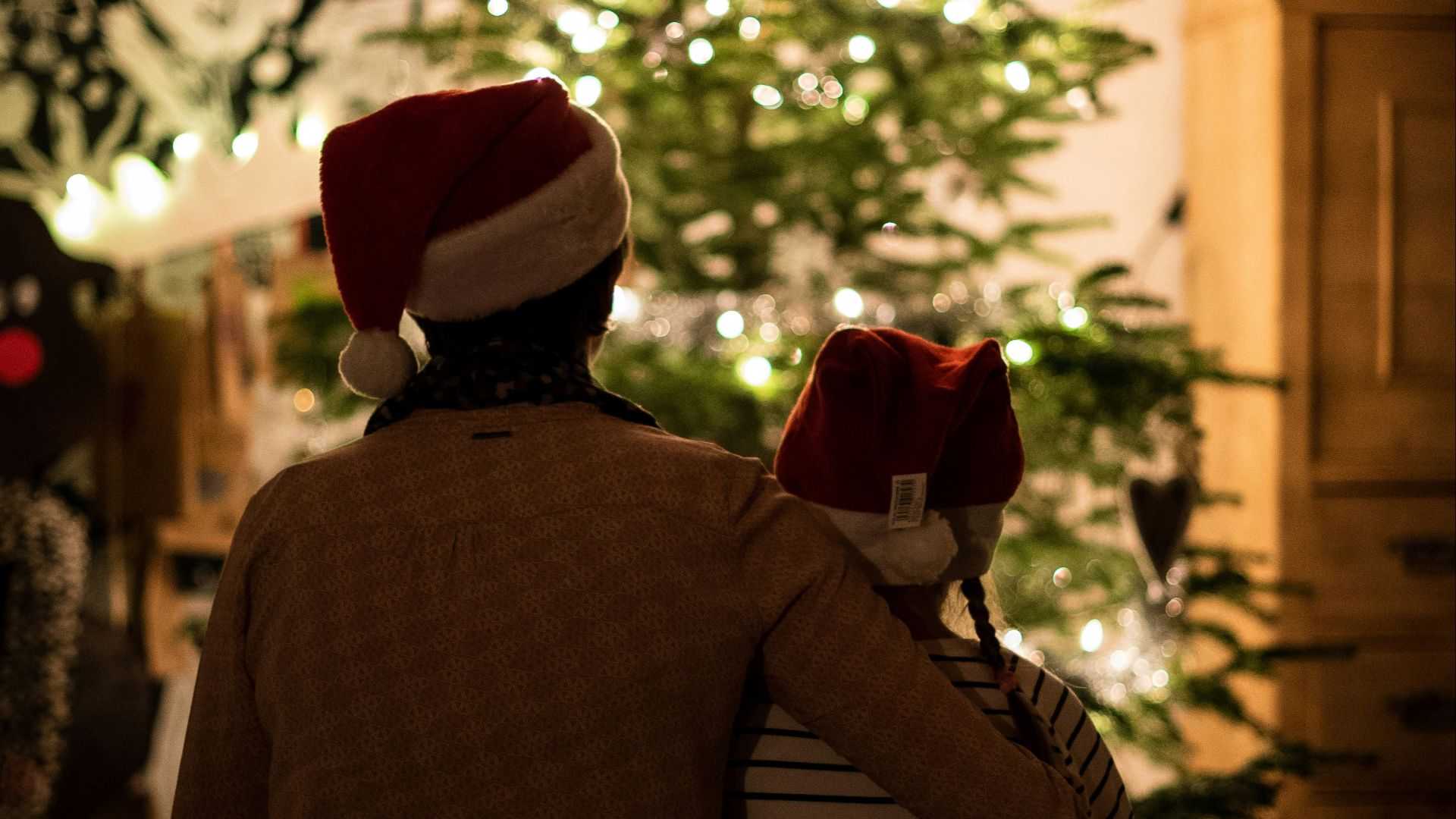 selective focus photography of girl an woman hugging each other in front of christmas tree