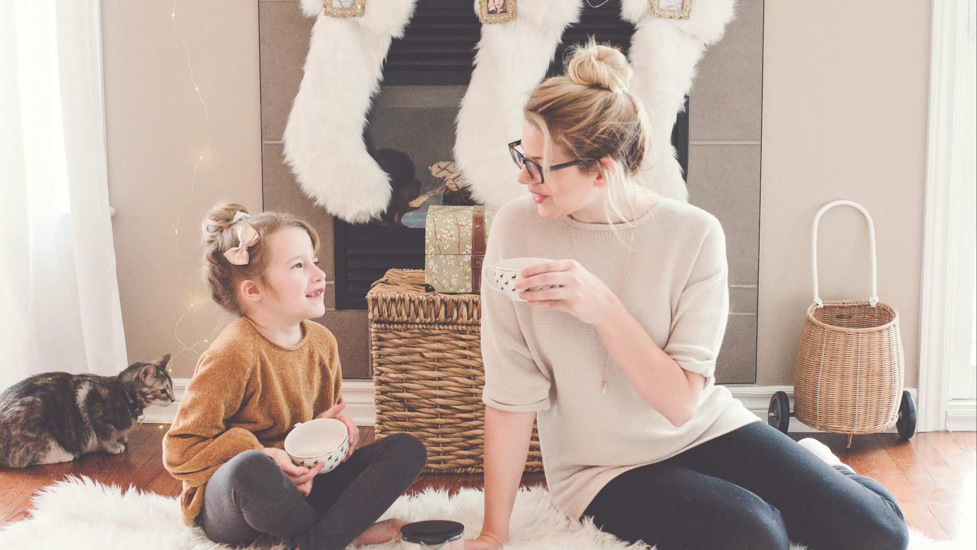 woman and girl sitting on white fur area rug