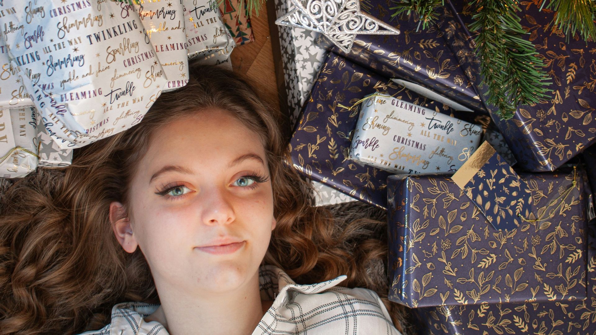 a young girl laying under a christmas tree