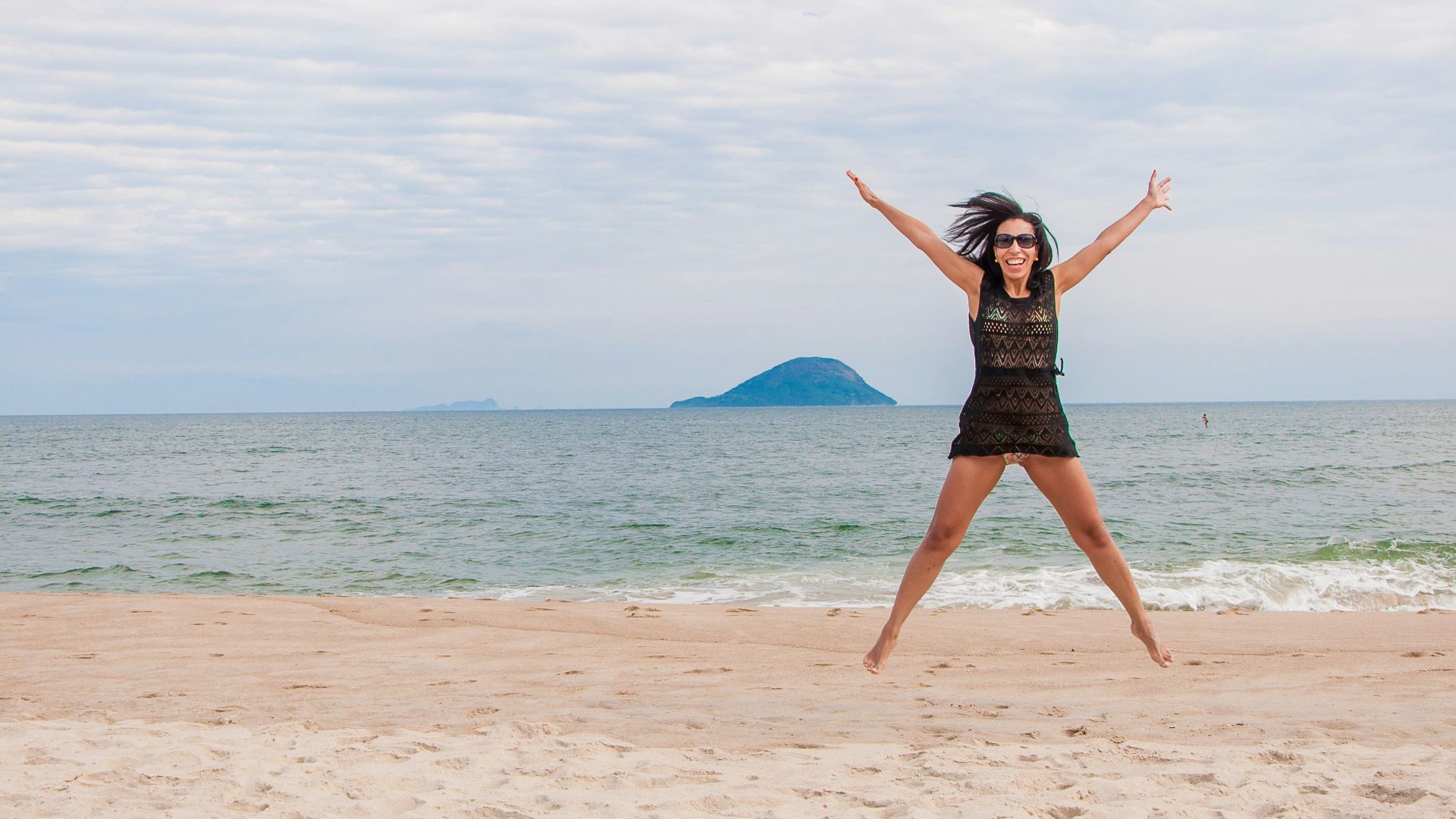 woman in black dress standing on beach during daytime