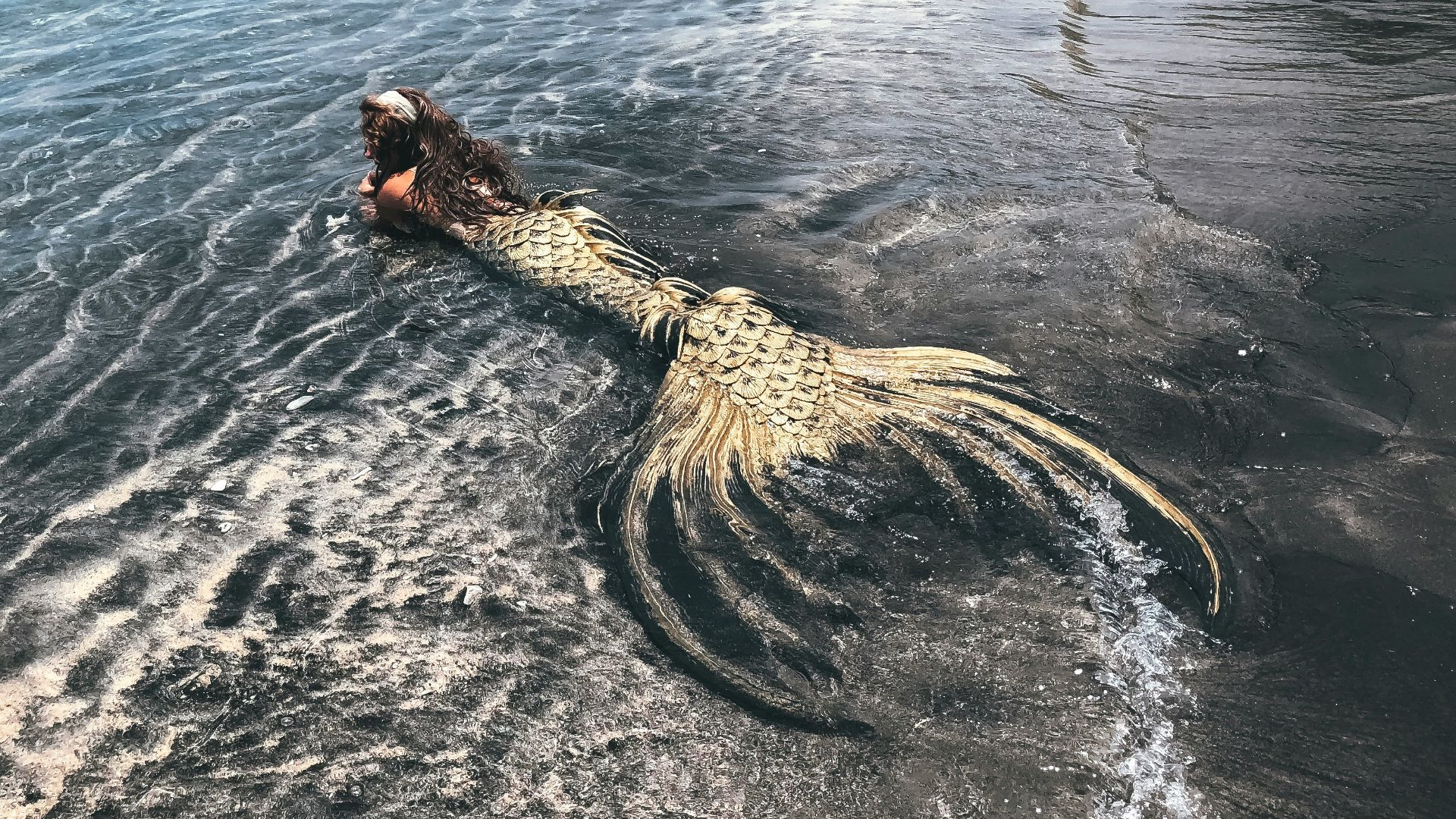 woman in black and white dress on brown rock formation on sea during daytime