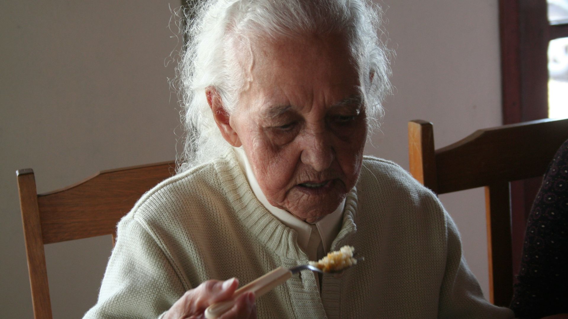 man in white sweater holding fork