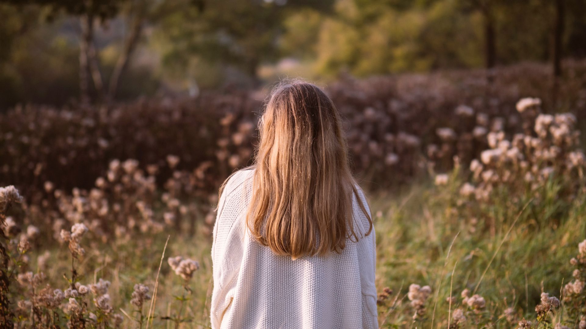 woman back surrounded by green and brown grass