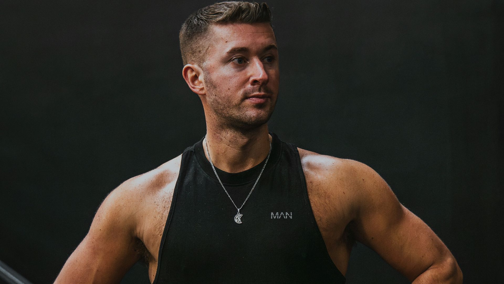 a man in a black tank top is standing with his hands on his hips