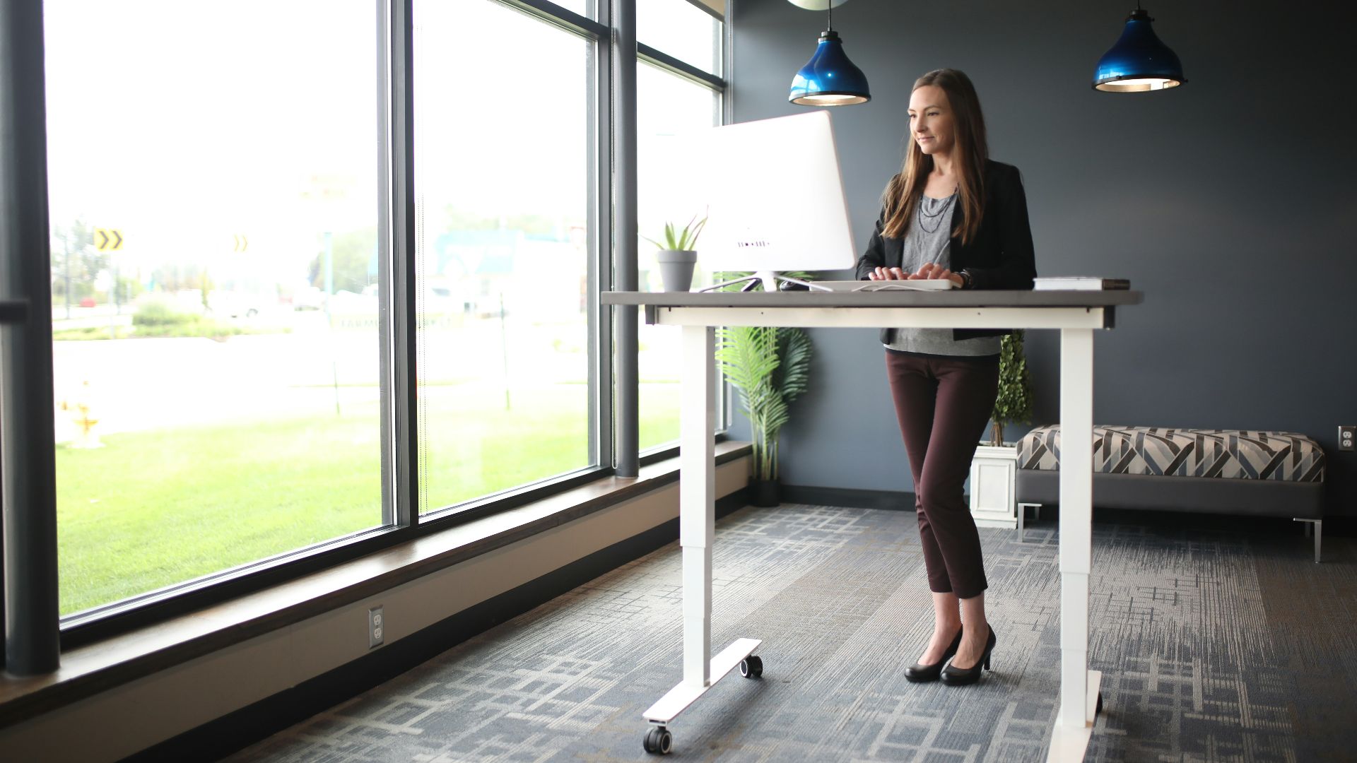 a woman standing at a desk in front of a window