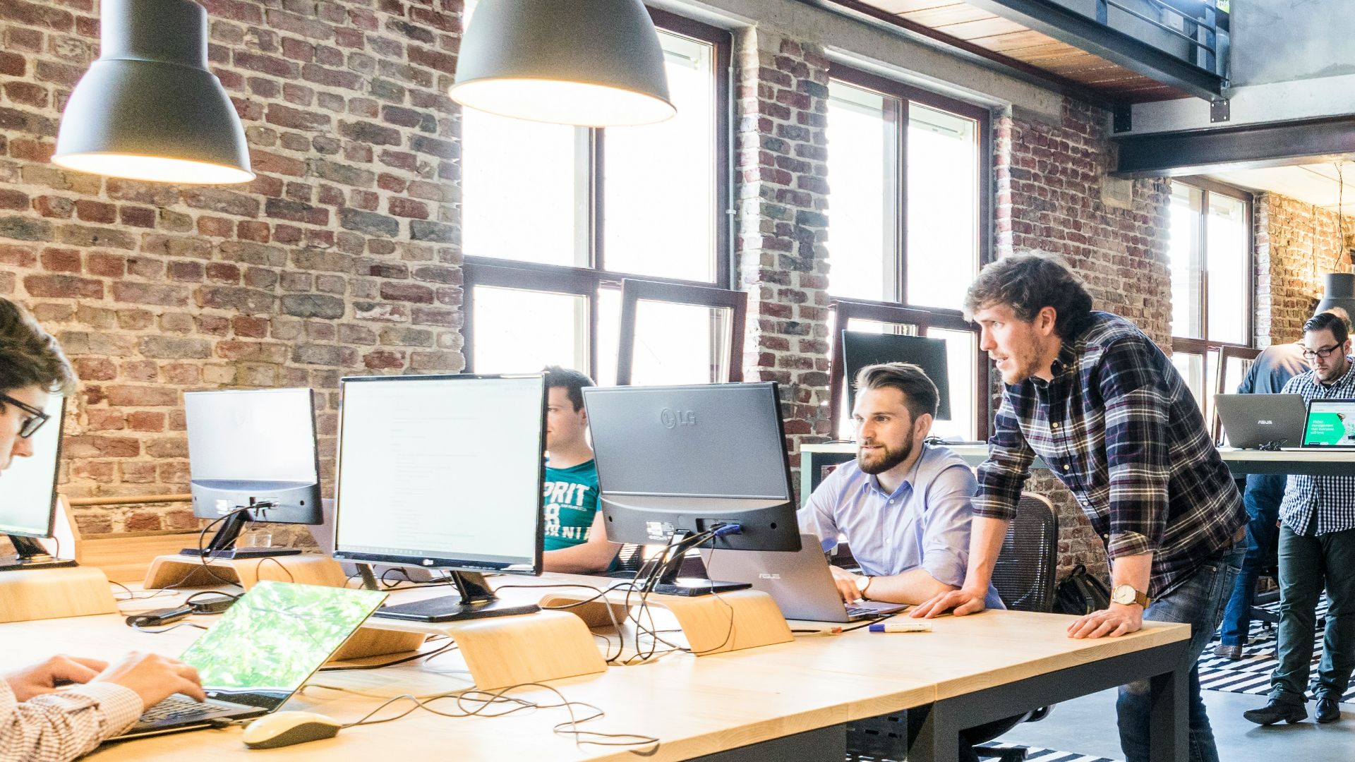 man standing beside another sitting man using computer