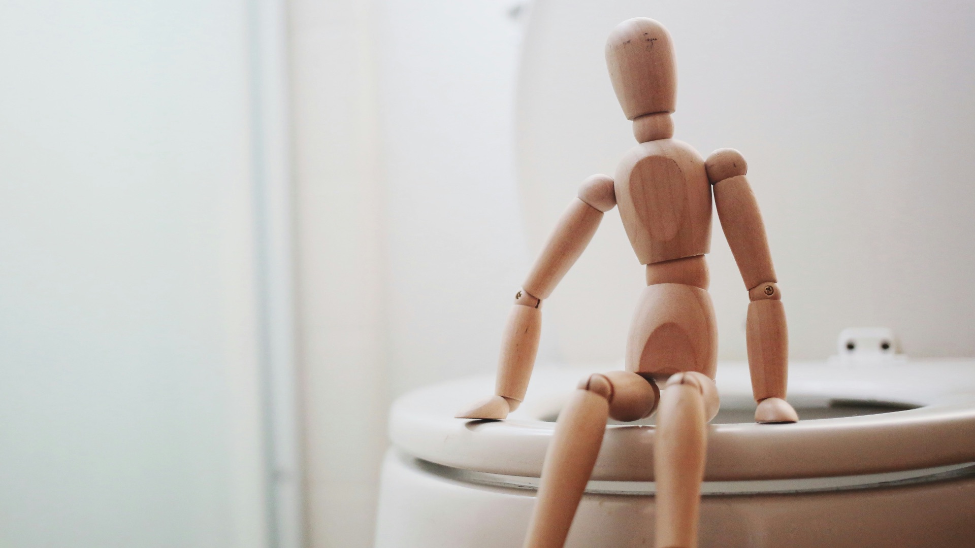 brown wooden doll on white ceramic toilet bowl