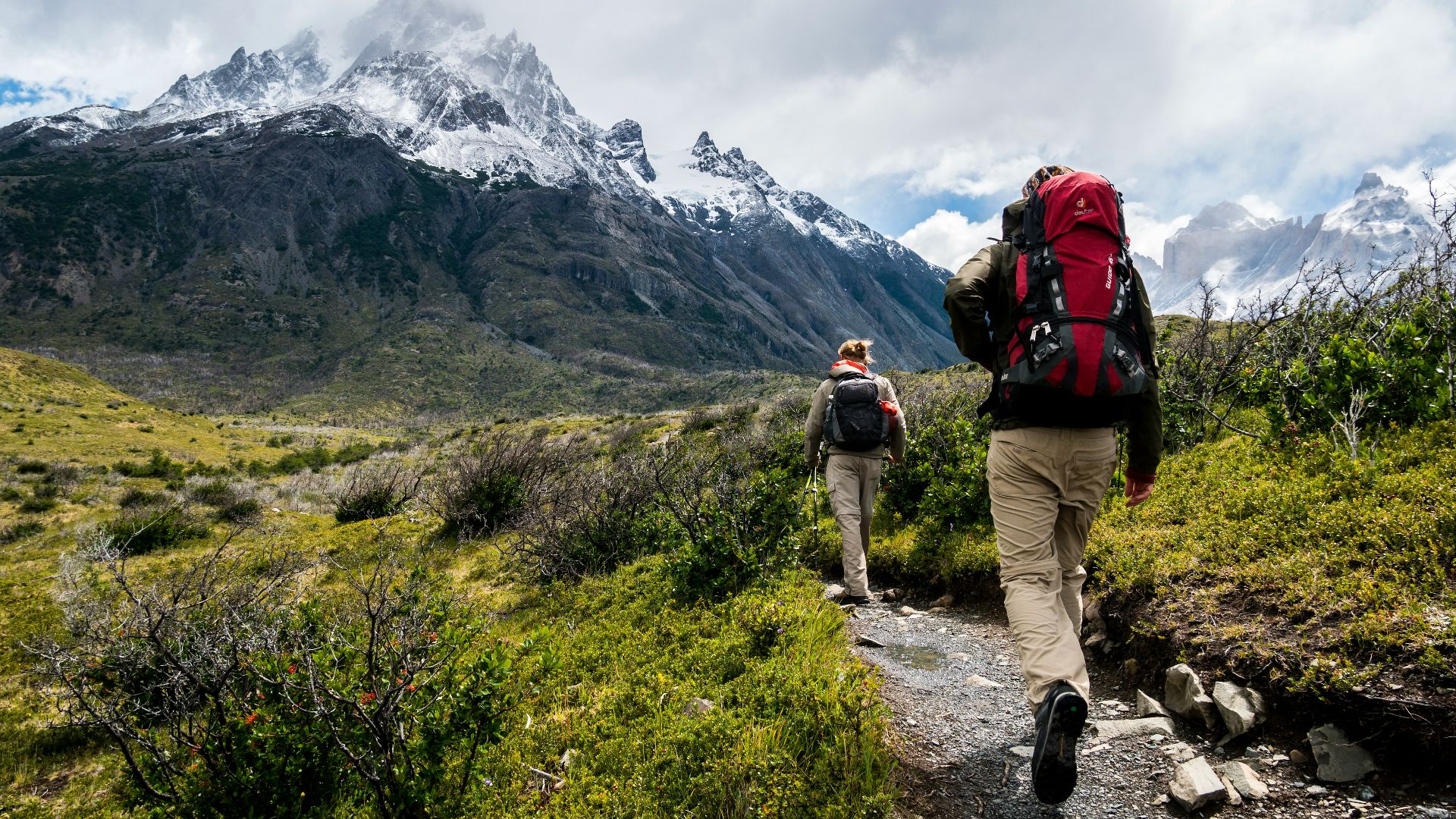 two person walking towards mountain covered with snow