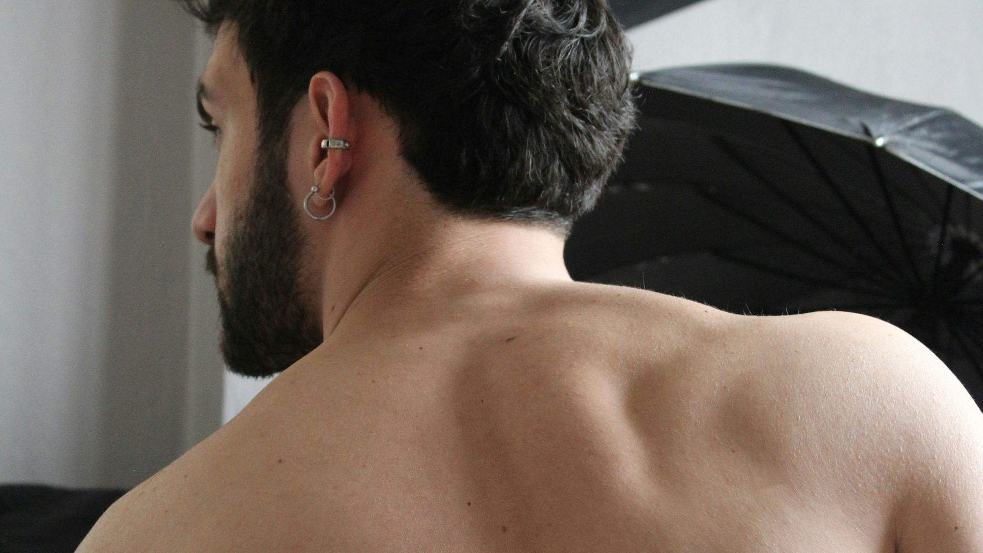 a man with no shirt standing in front of a black umbrella