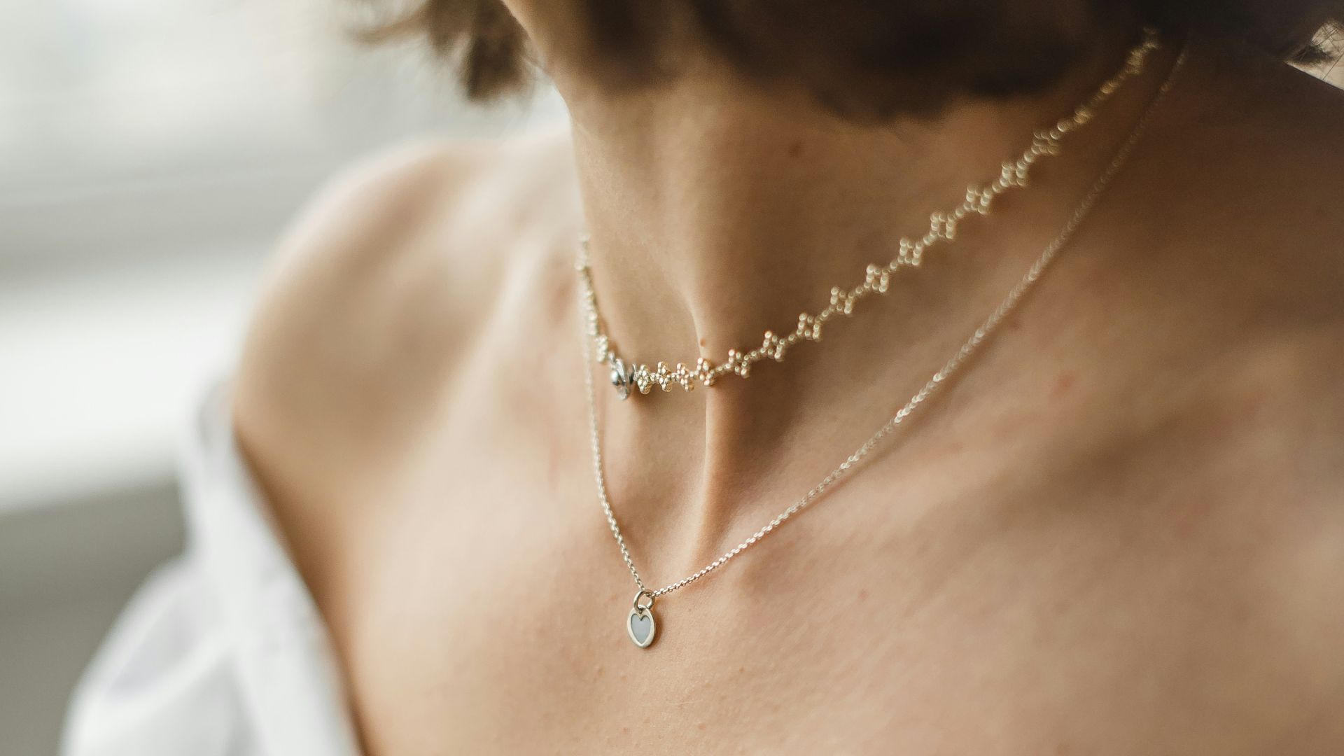 woman in white off shoulder shirt wearing silver necklace