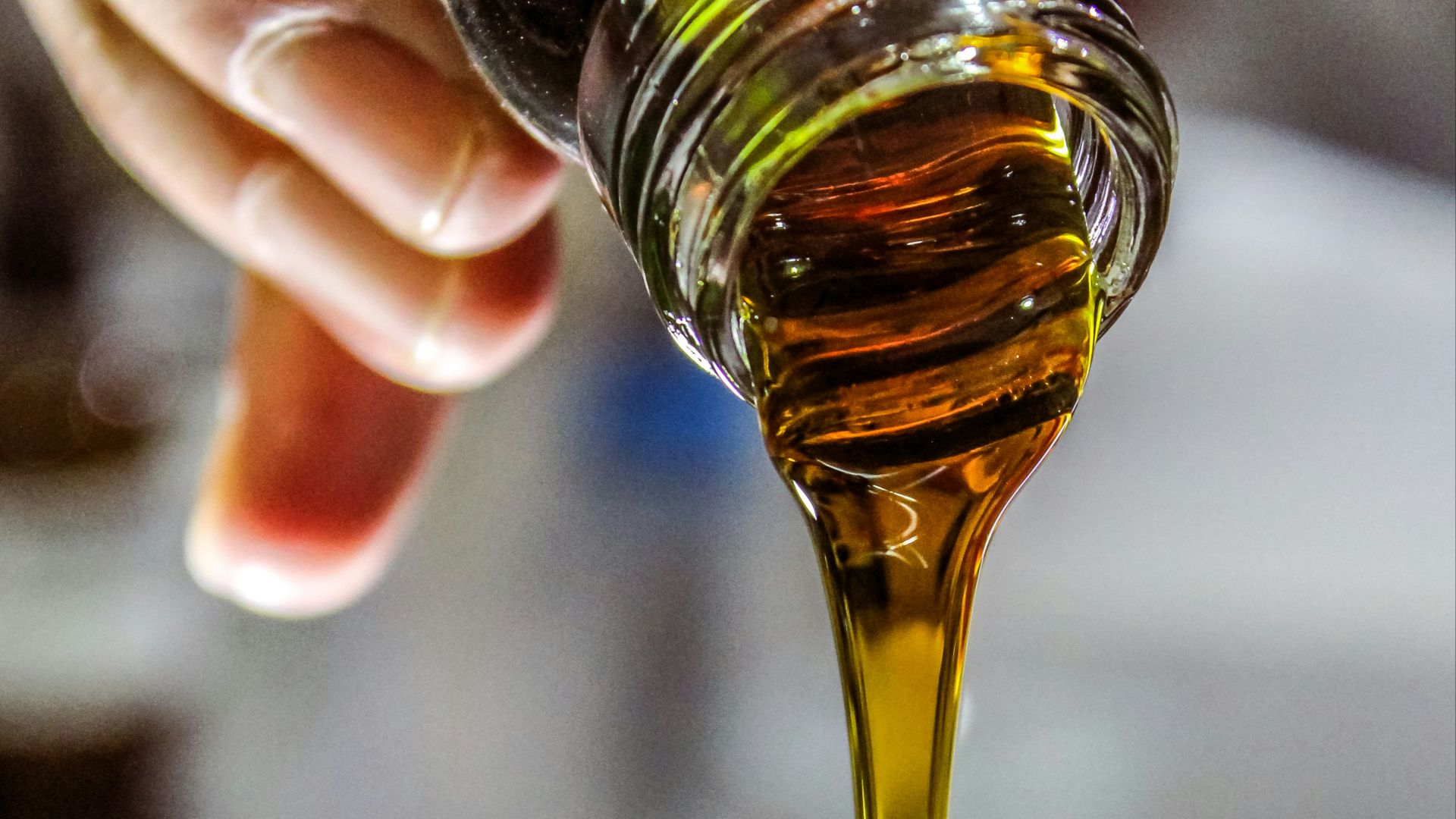 person holding clear drinking glass with brown liquid