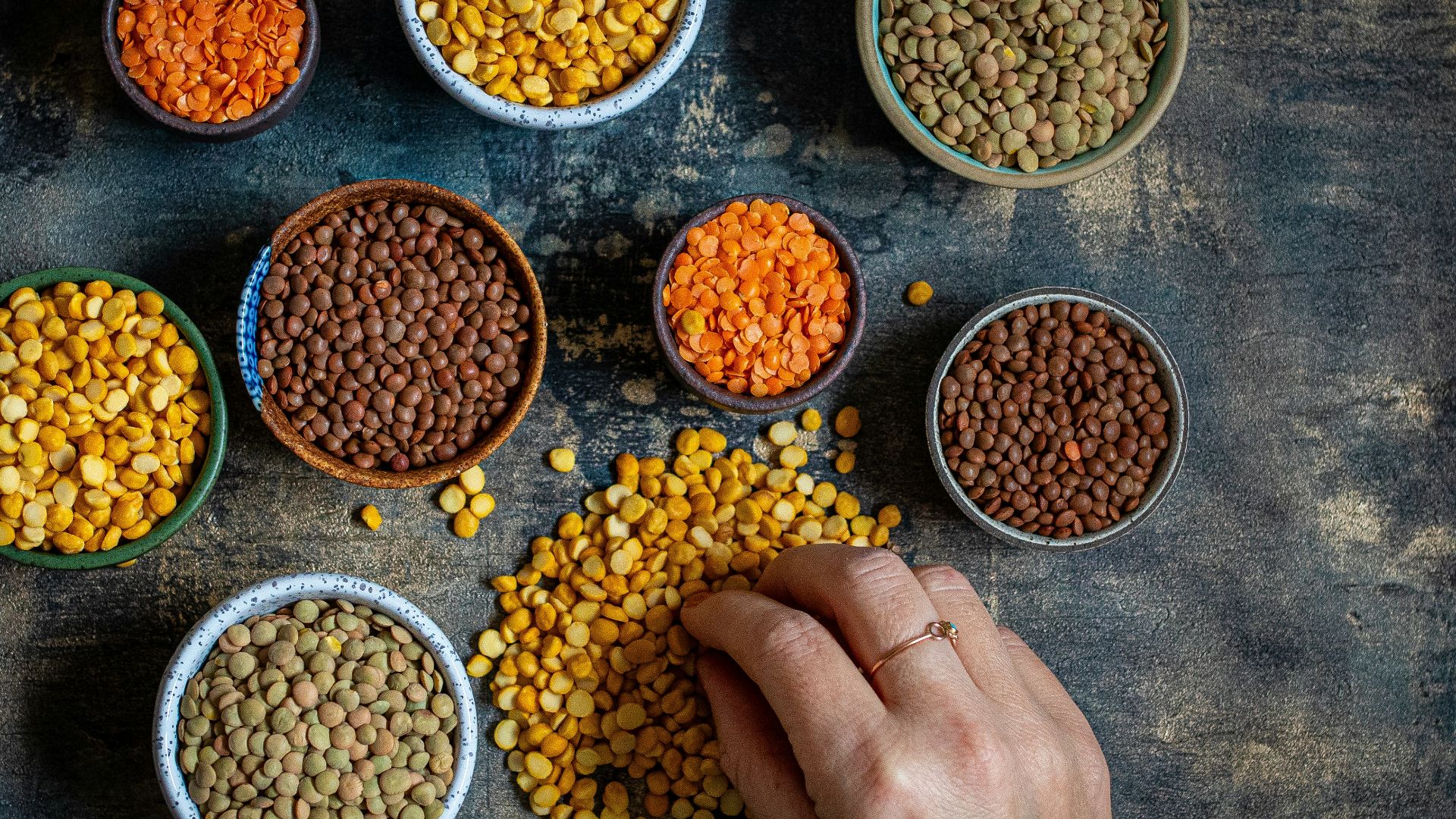 a person touching a bowl of lentils on a table