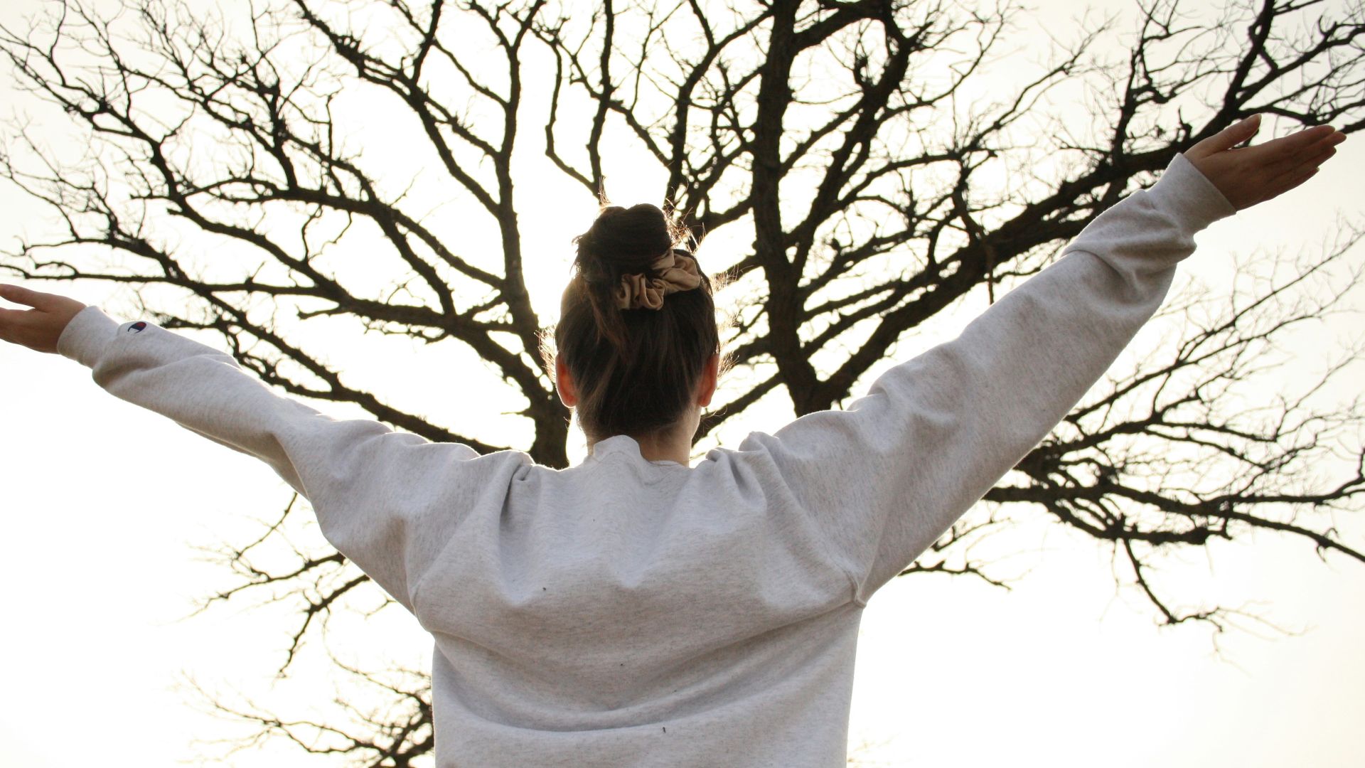 woman in white long sleeve shirt standing near bare tree during daytime