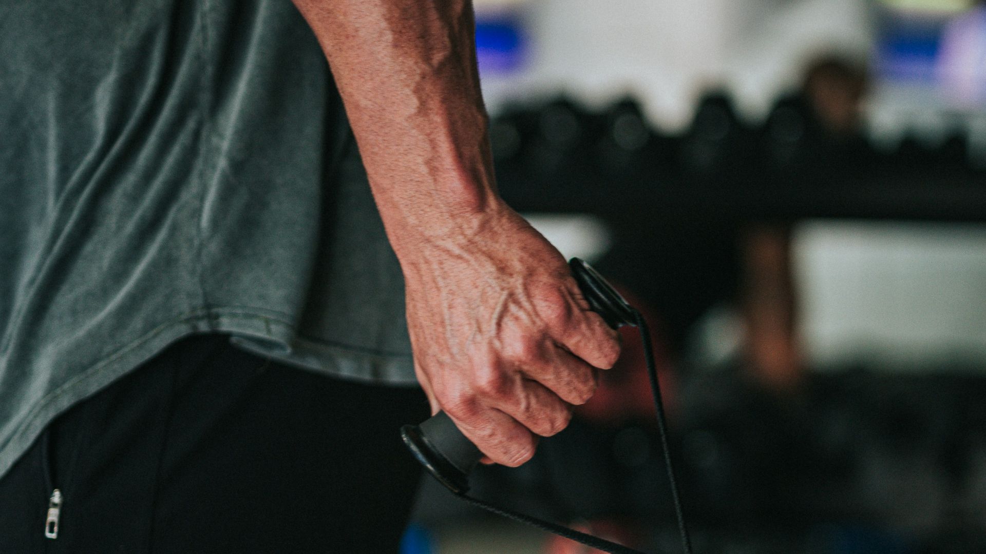 man in gray t-shirt and black pants holding black corded headphones