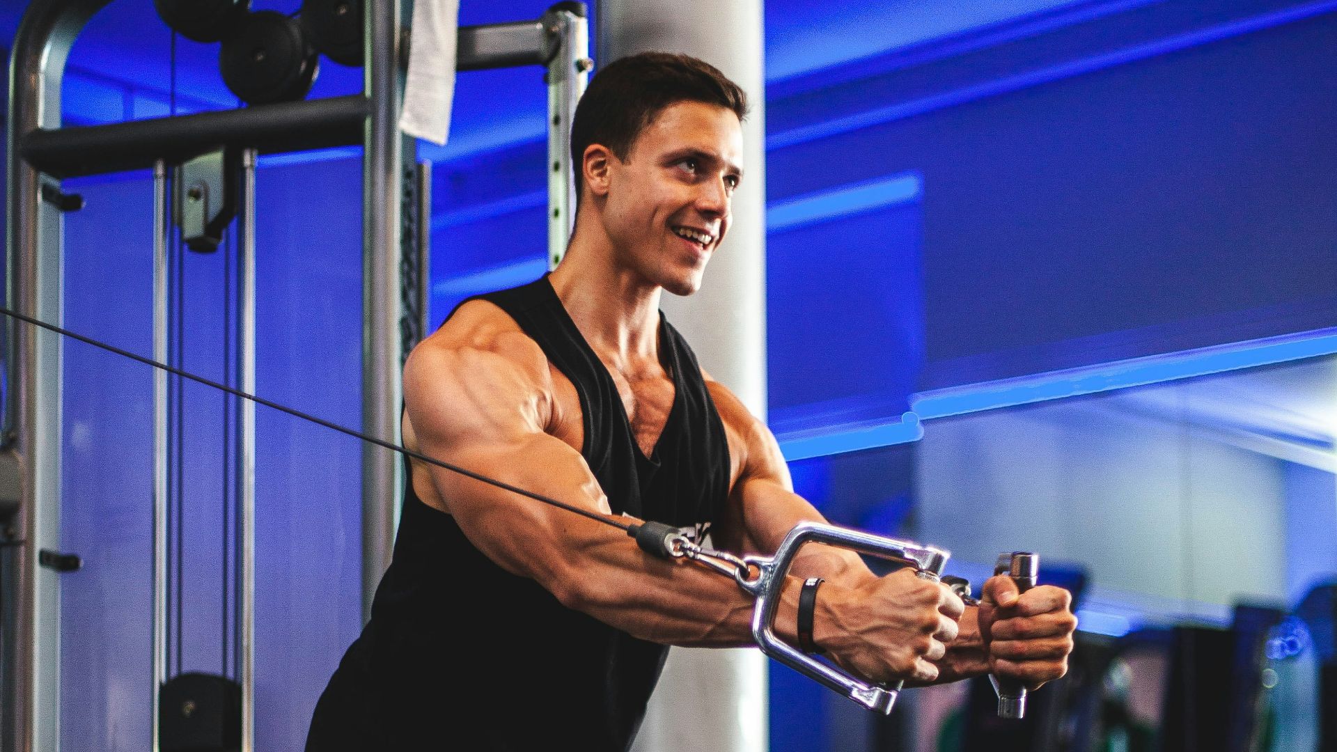 man in black tank top and gray shorts holding black smartphone