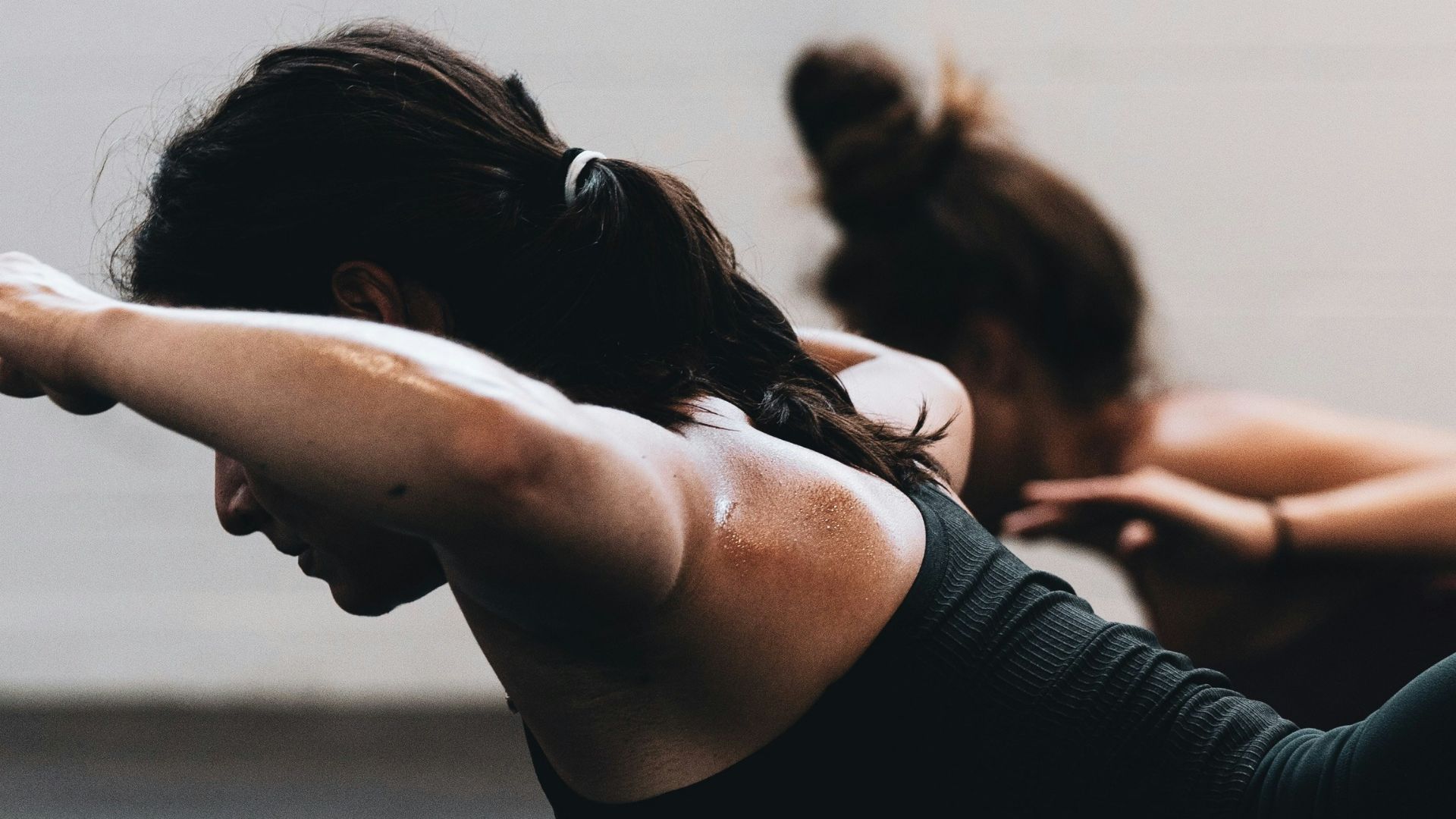 woman in black tank top and black leggings lying on black floor
