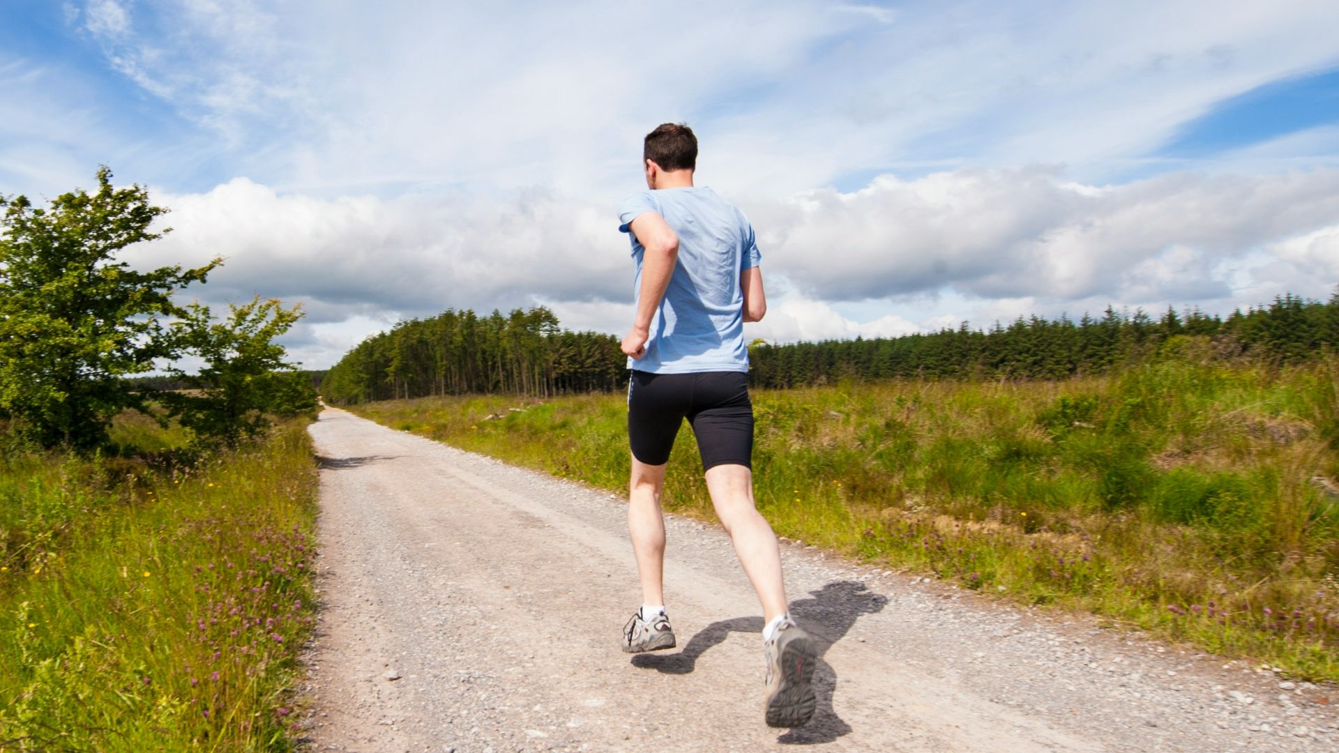 man running on road near grass field