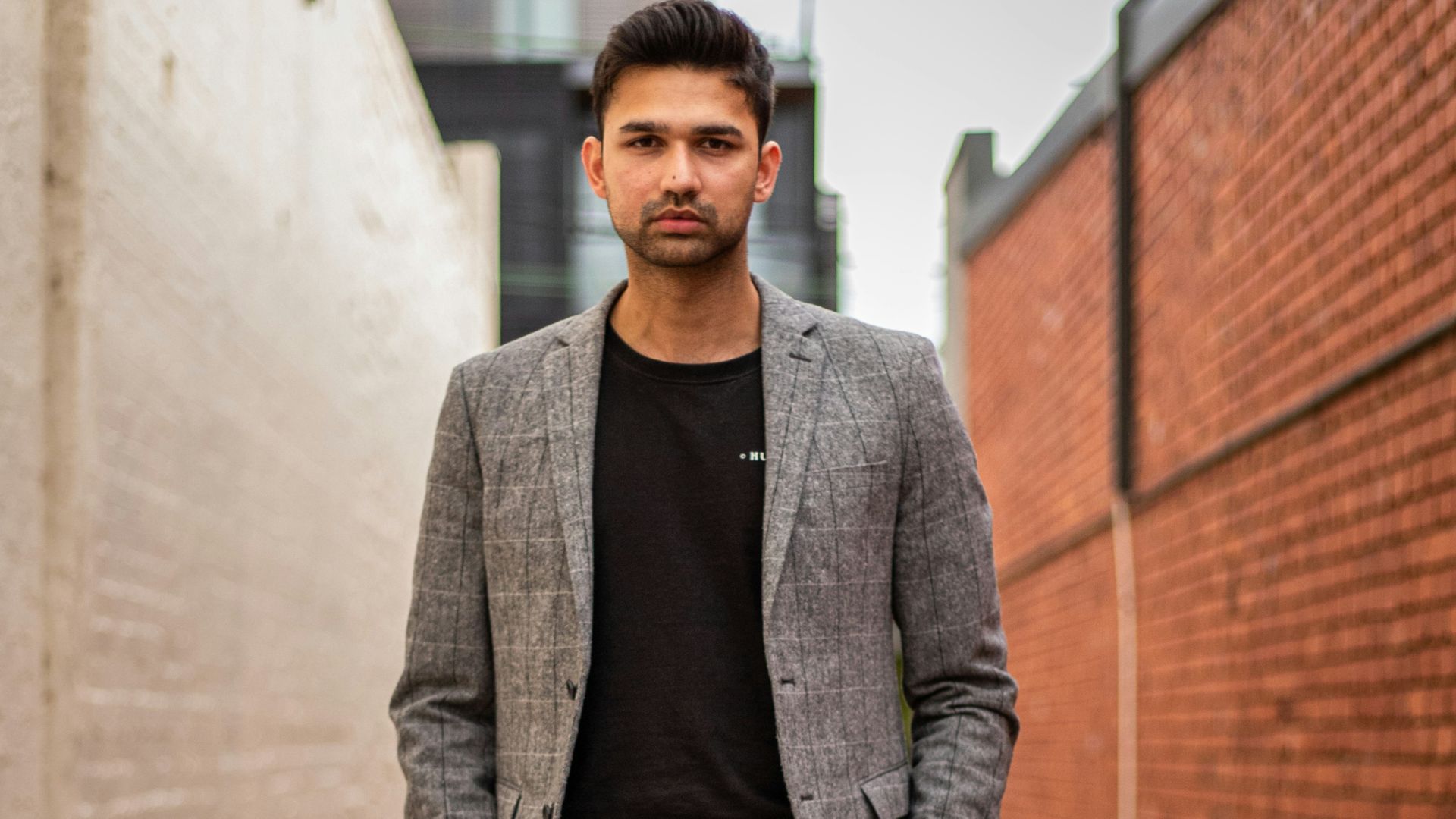 man in gray suit jacket and black pants standing on brown concrete pathway during daytime