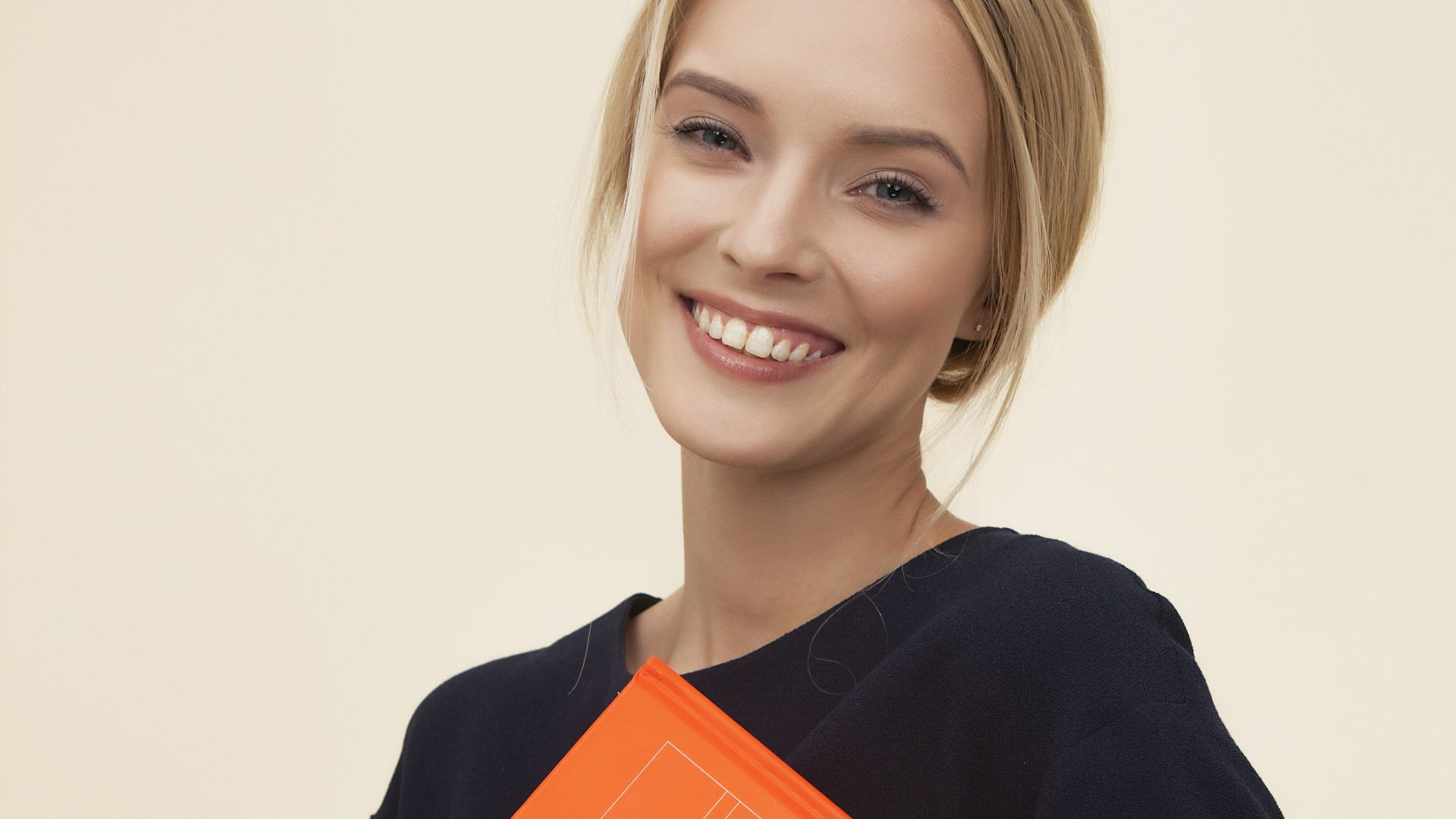 smiling woman standing while holding orange folder