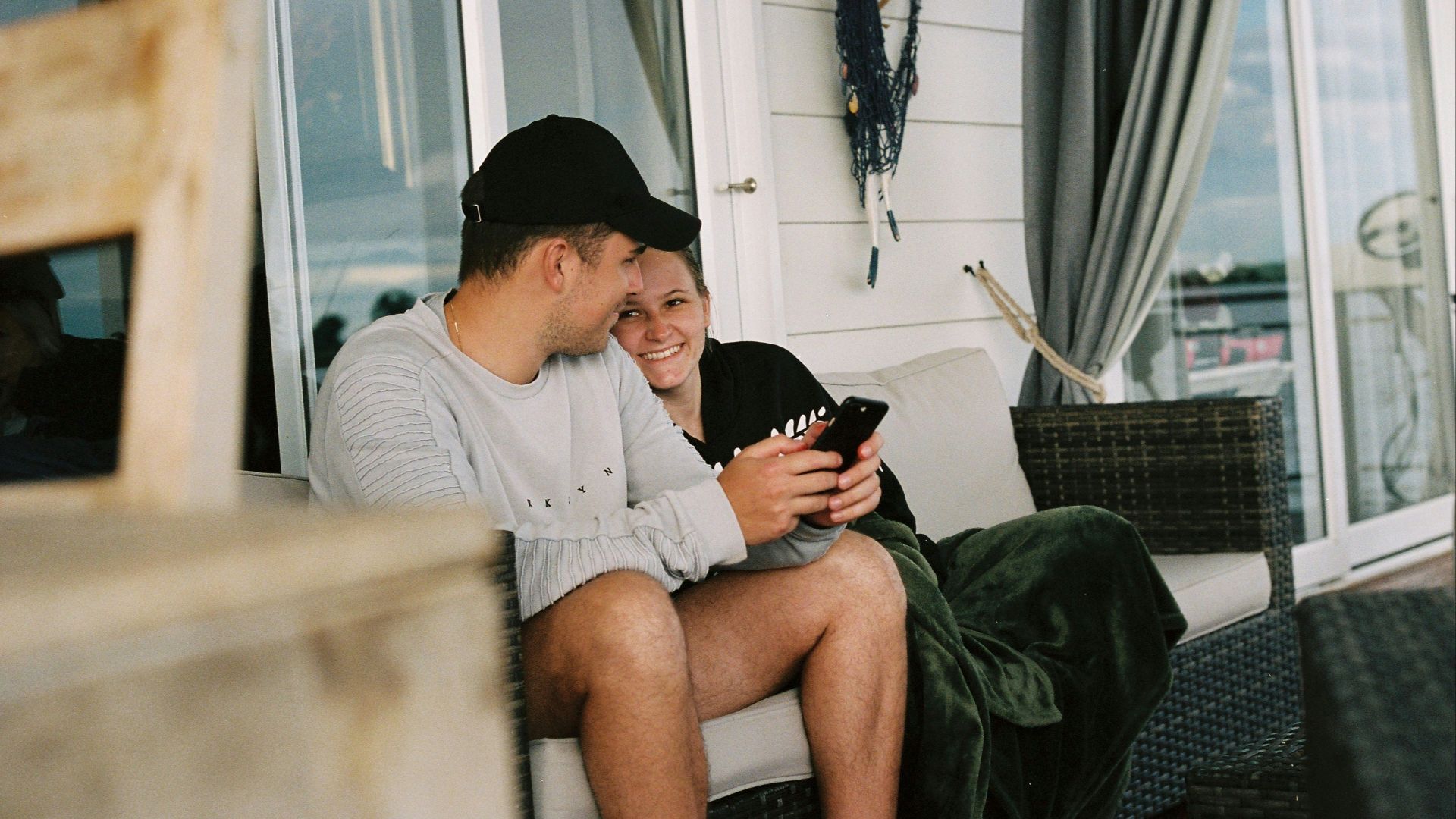 a man and woman sitting on a bench looking at their phones