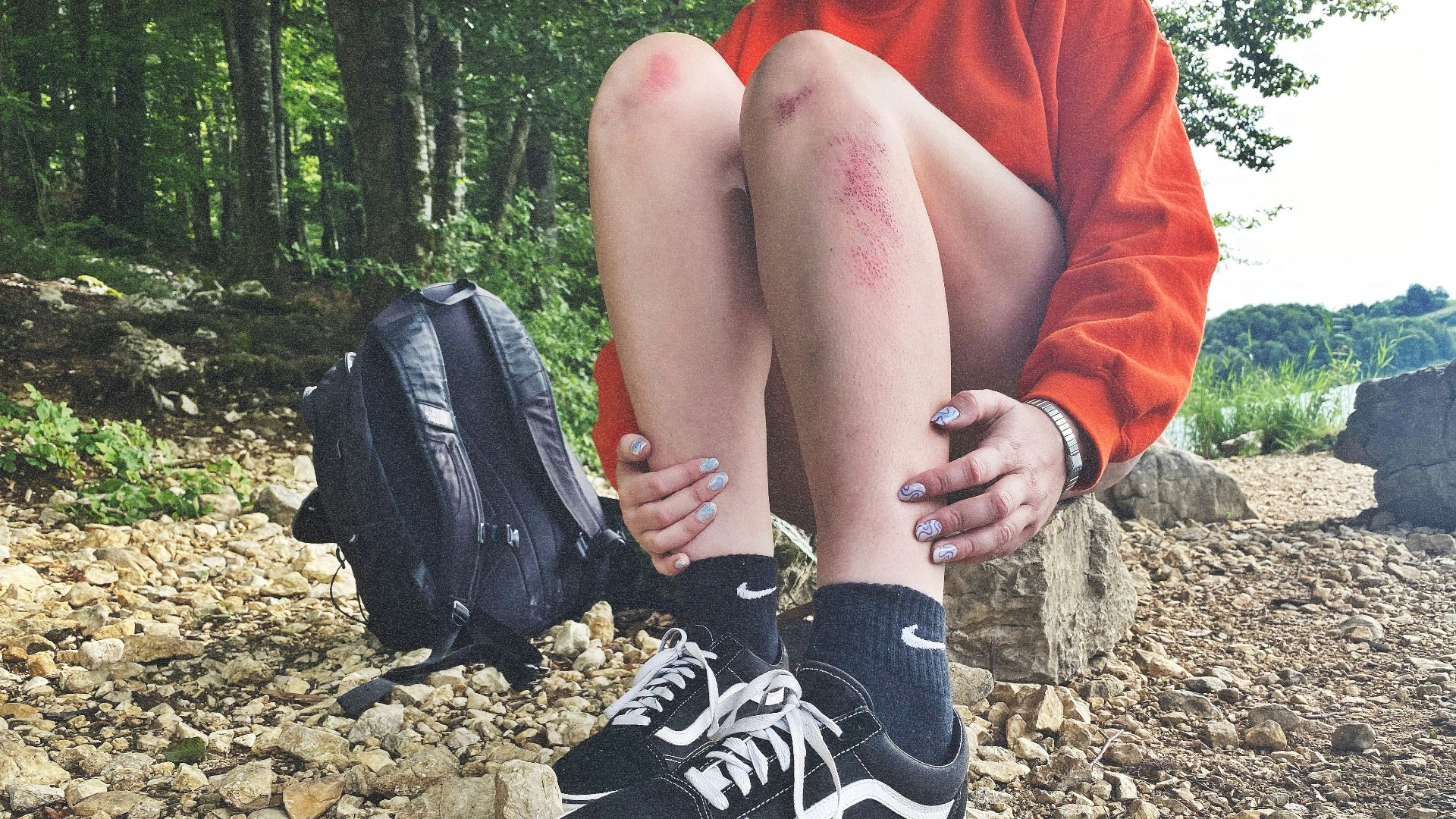 person in black and white nike athletic shoes sitting on rocky ground