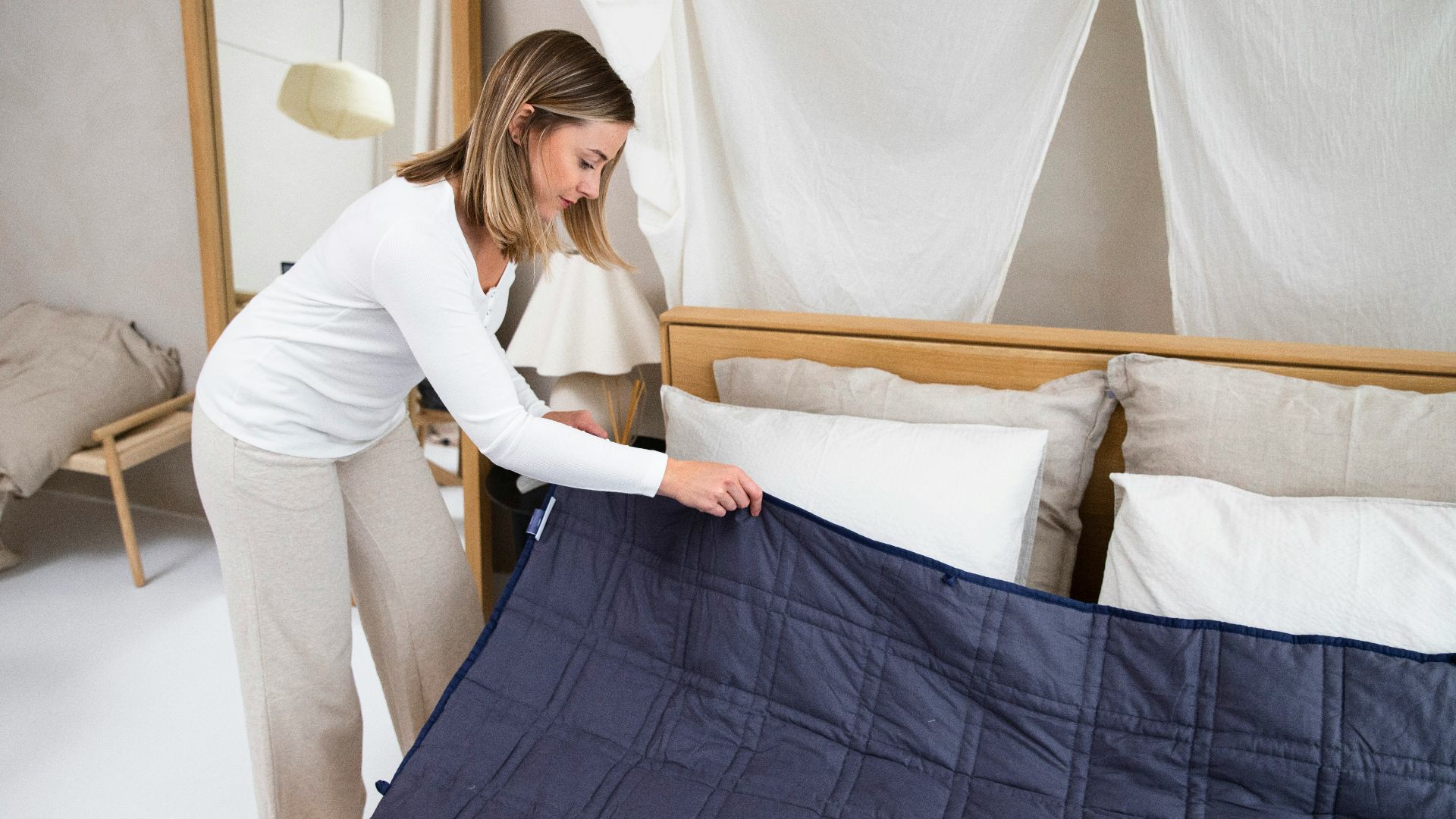 a woman putting a blue blanket on top of a bed