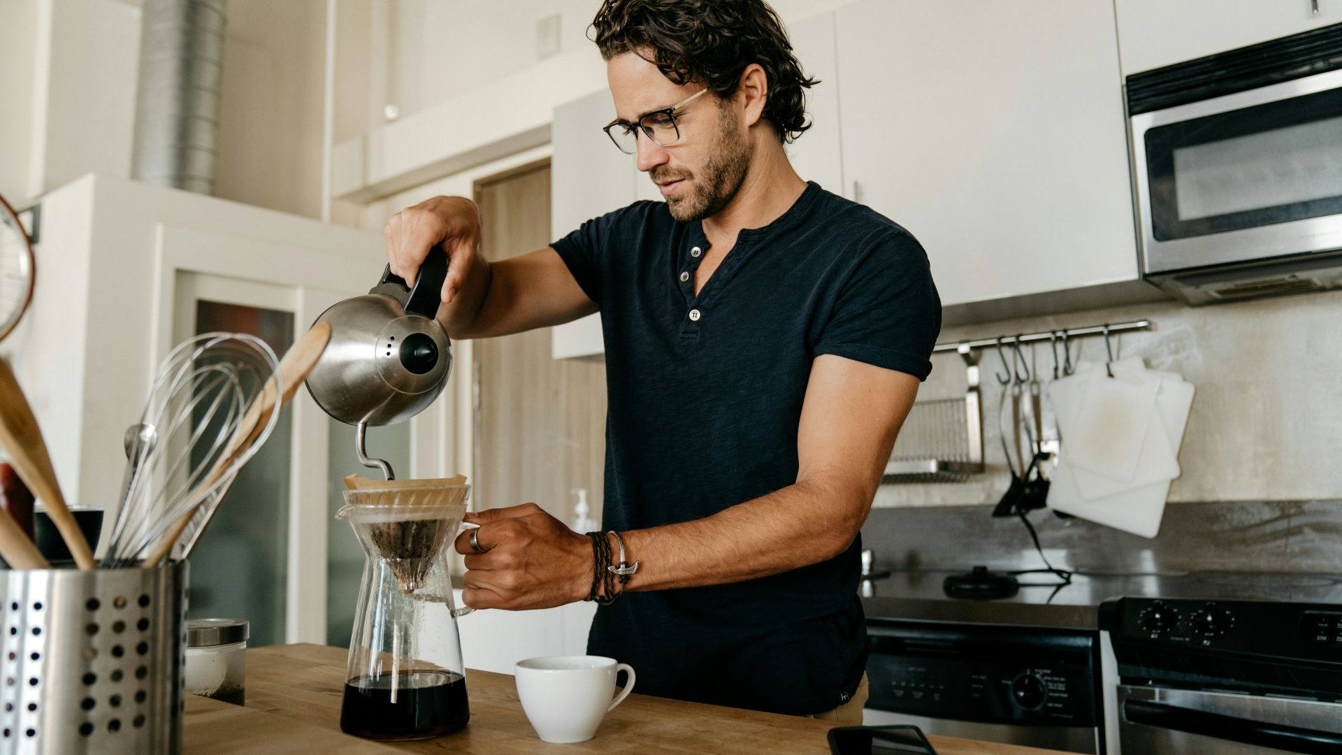 man in blue crew neck t-shirt pouring water on white ceramic teacup
