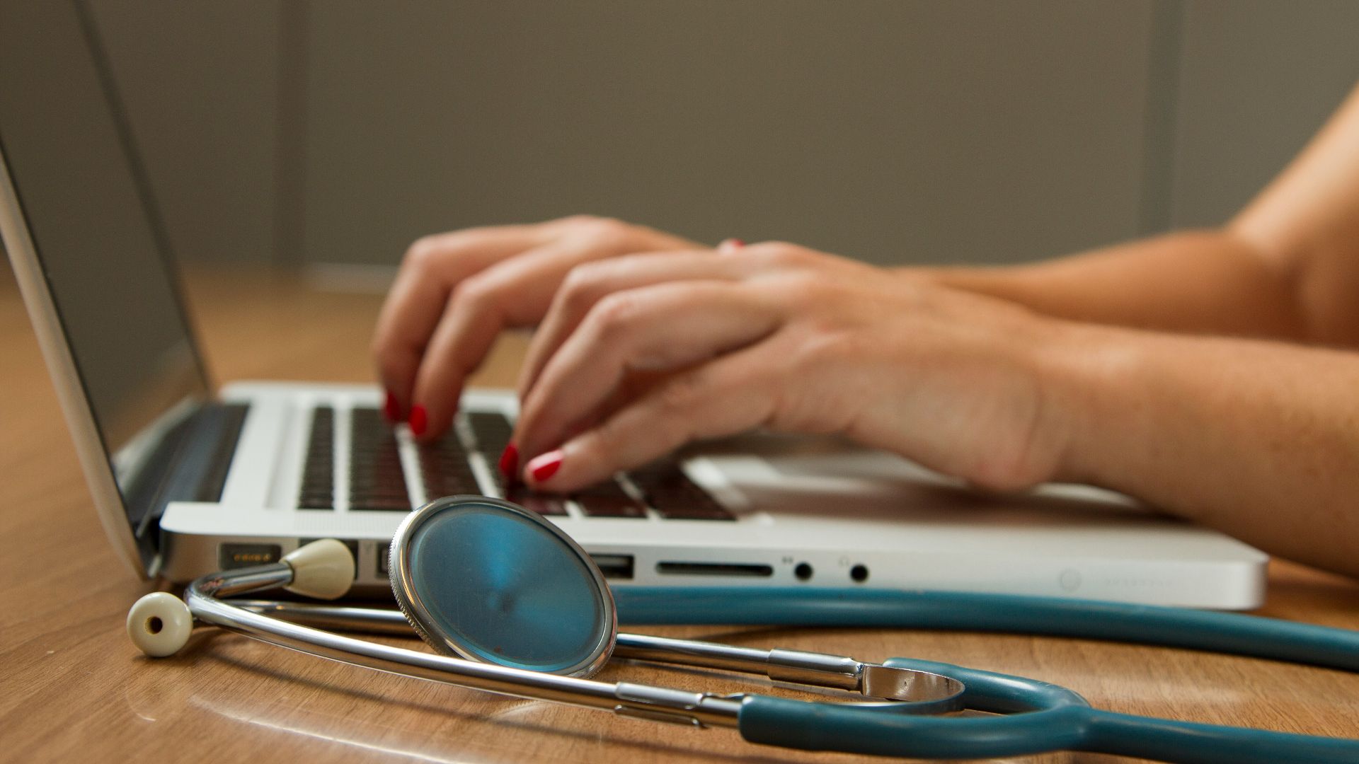 person sitting while using laptop computer and green stethoscope near