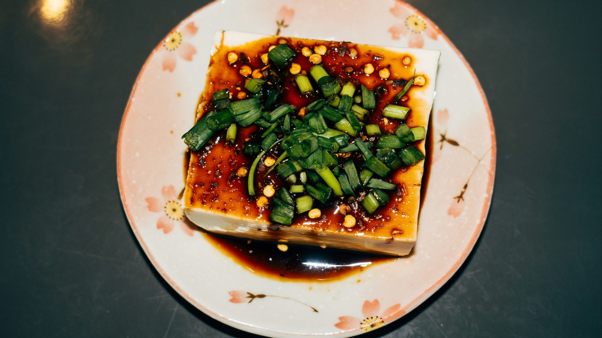 Tofu dish topped with greens and sauce.