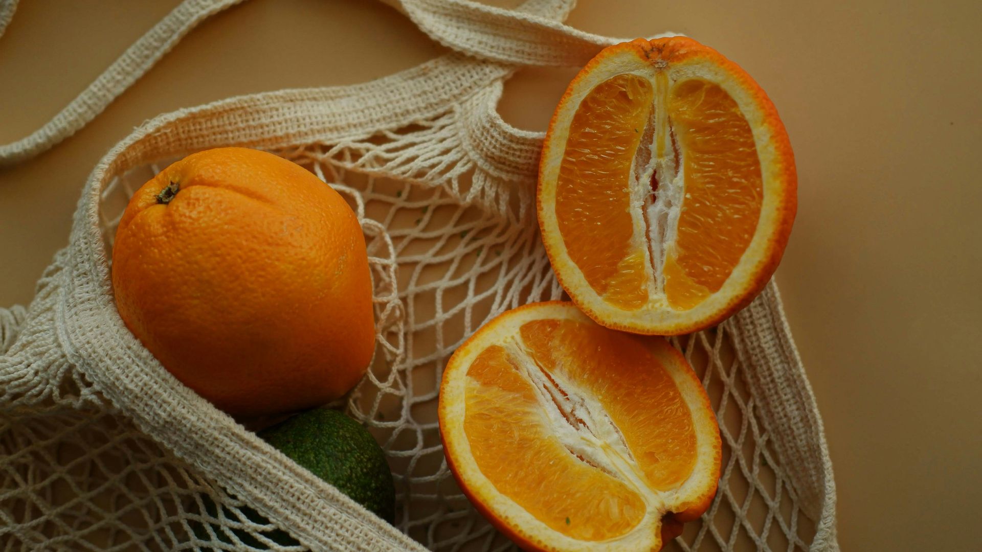 two oranges and one avocado in a bag