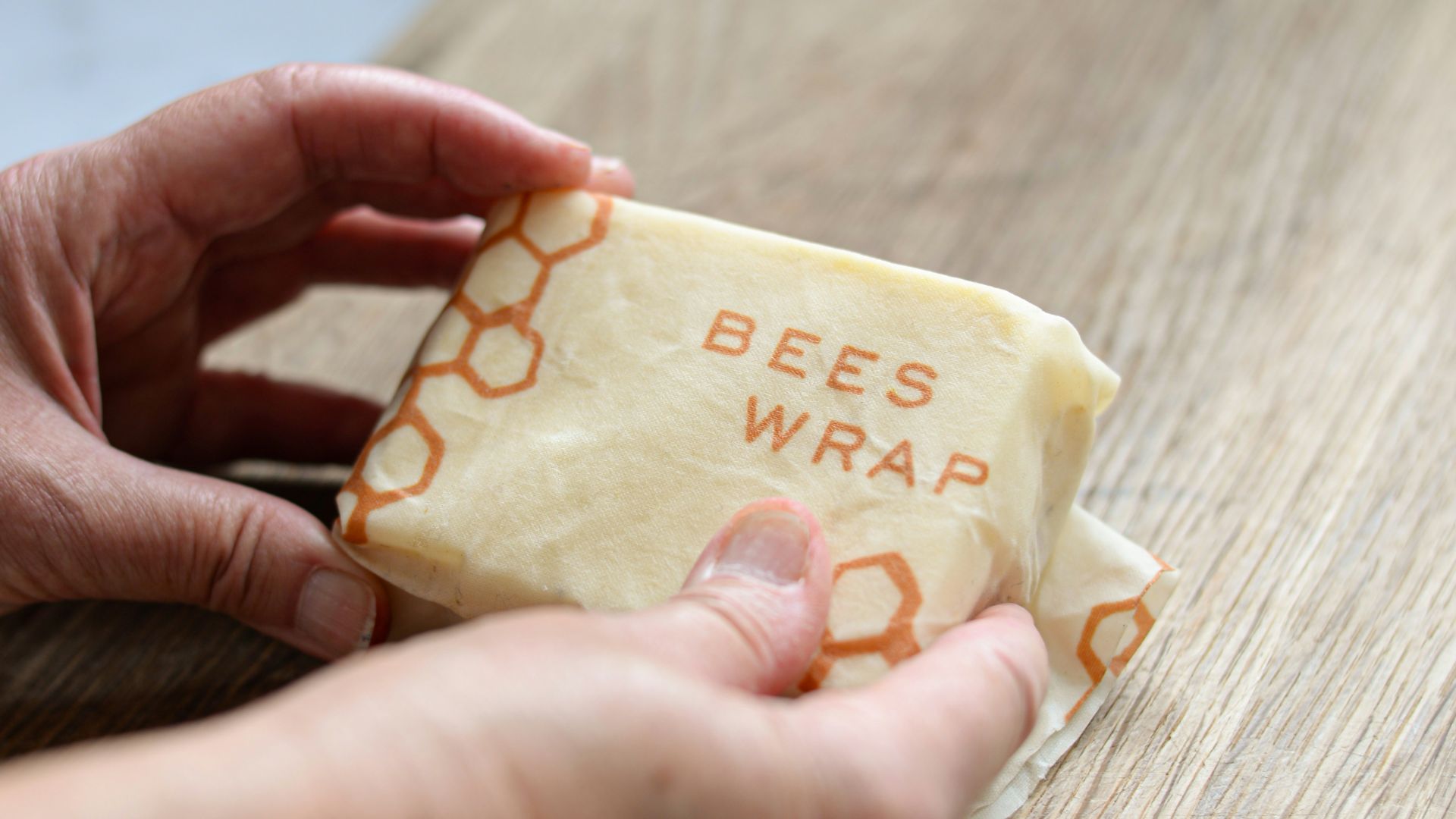 a person holding a piece of cheese on a cutting board
