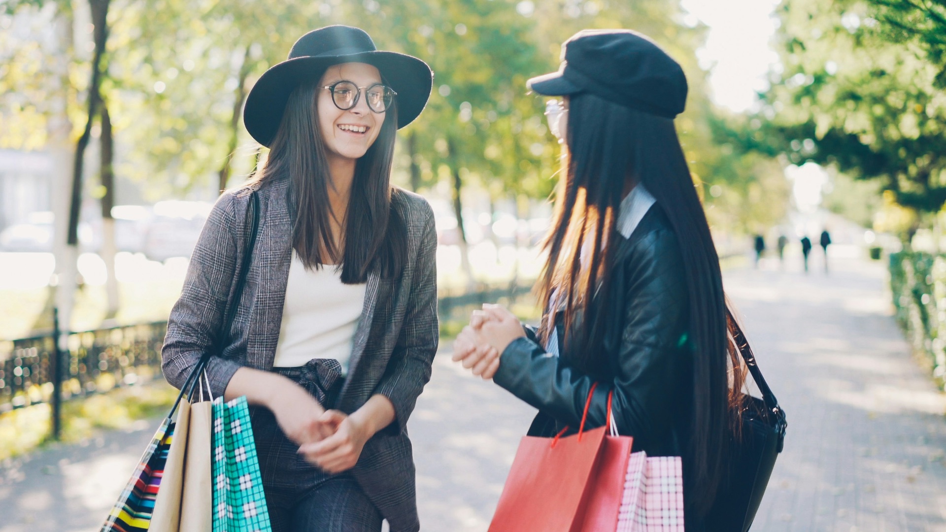 Two women with shopping bags walk outdoors.