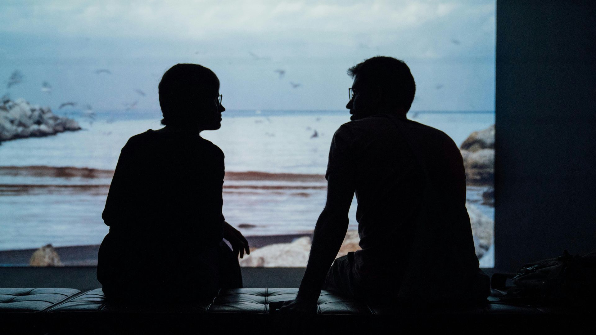 silhouette of man and woman sitting on ottoman