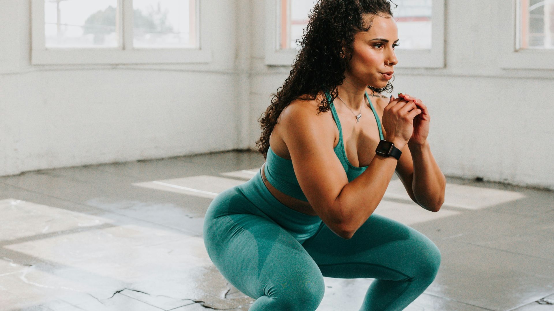 a woman squatting on the floor in a gym