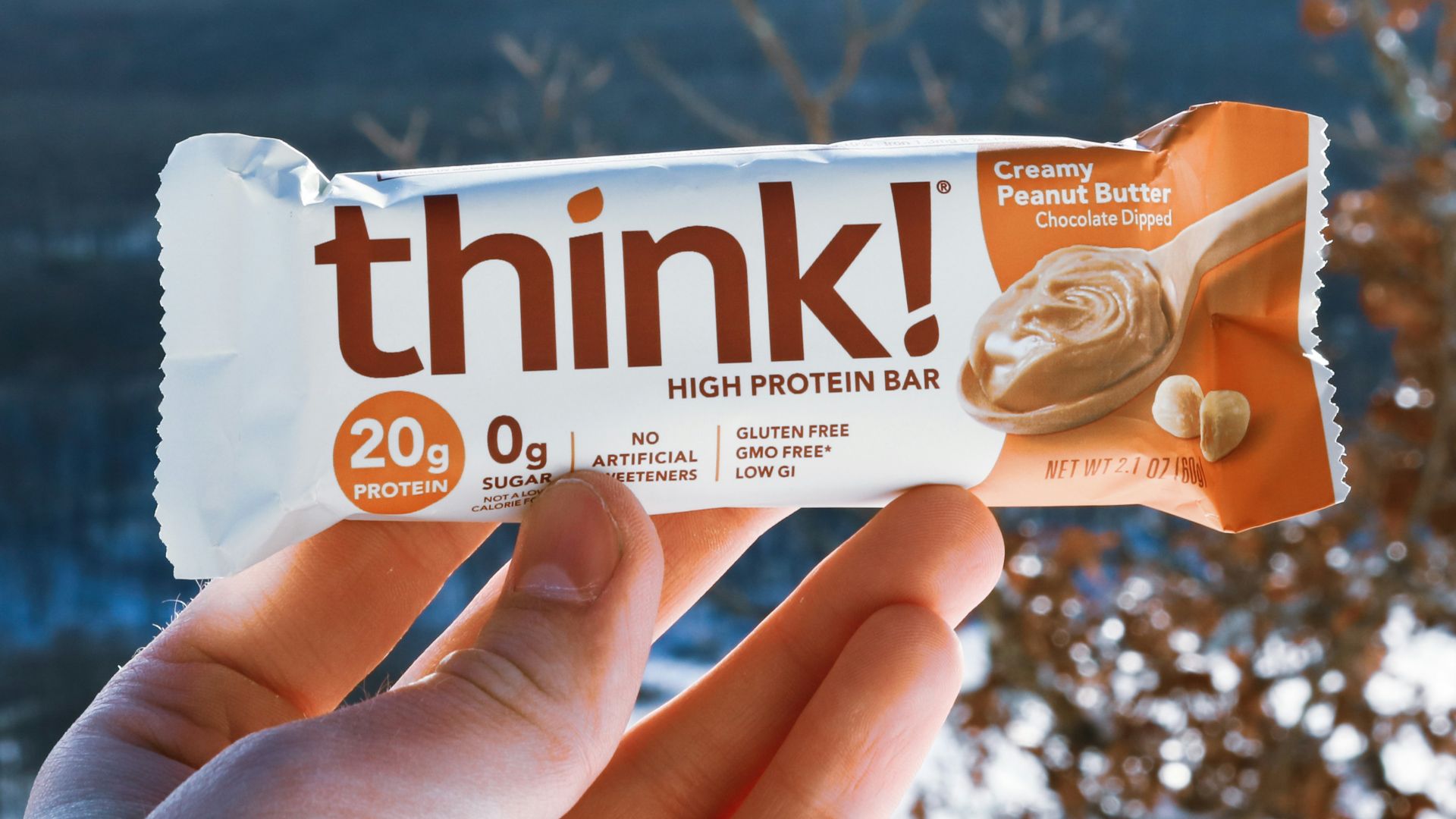 a hand holding a bar of think with a mountain in the background