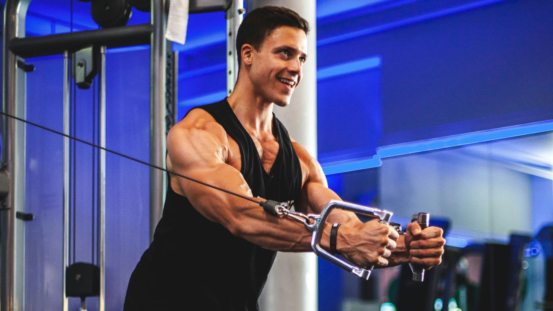 man in black tank top and gray shorts holding black smartphone