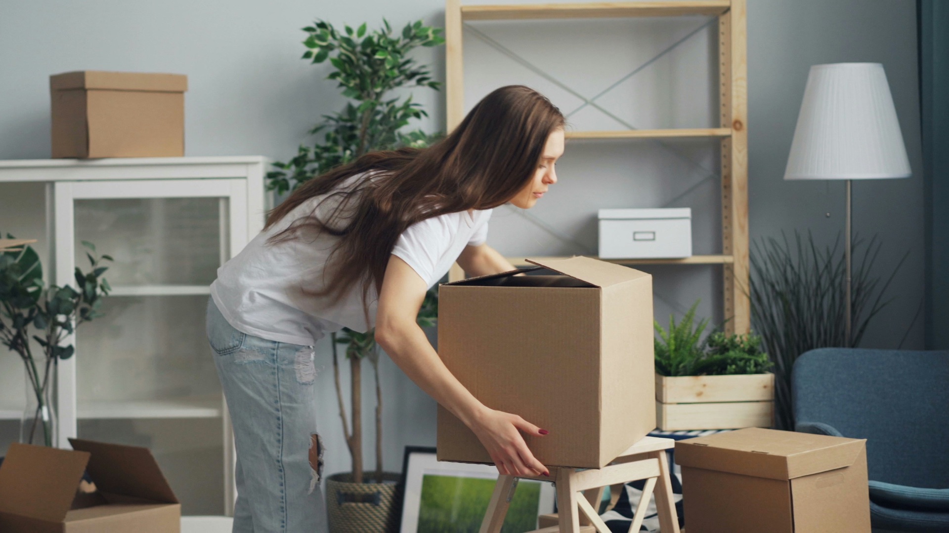 a woman moving boxes in a living room