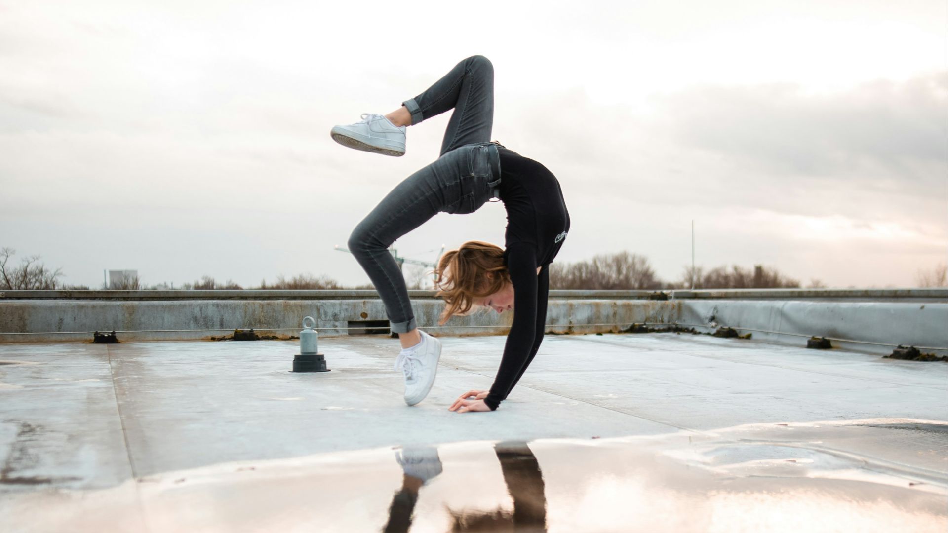 woman doing bridge posts reflecting on water puddle