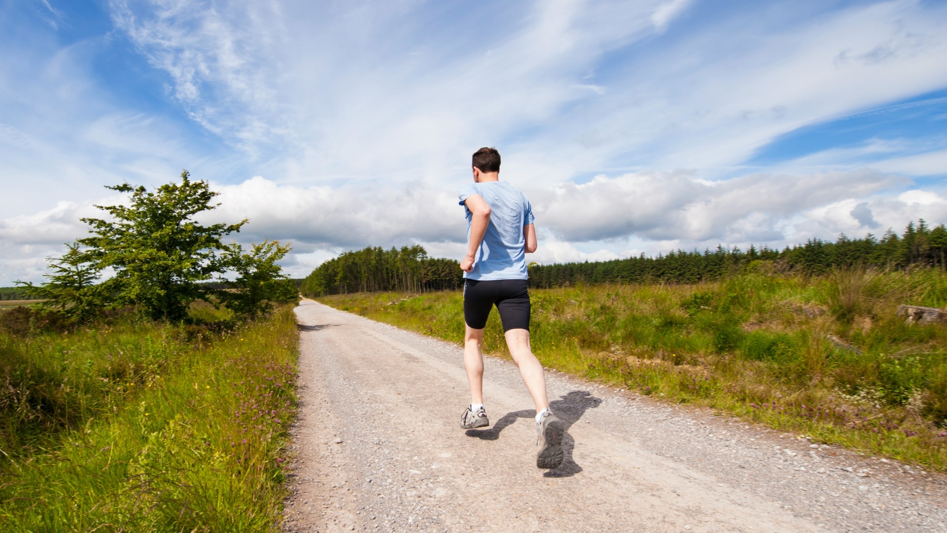 man running on road near grass field