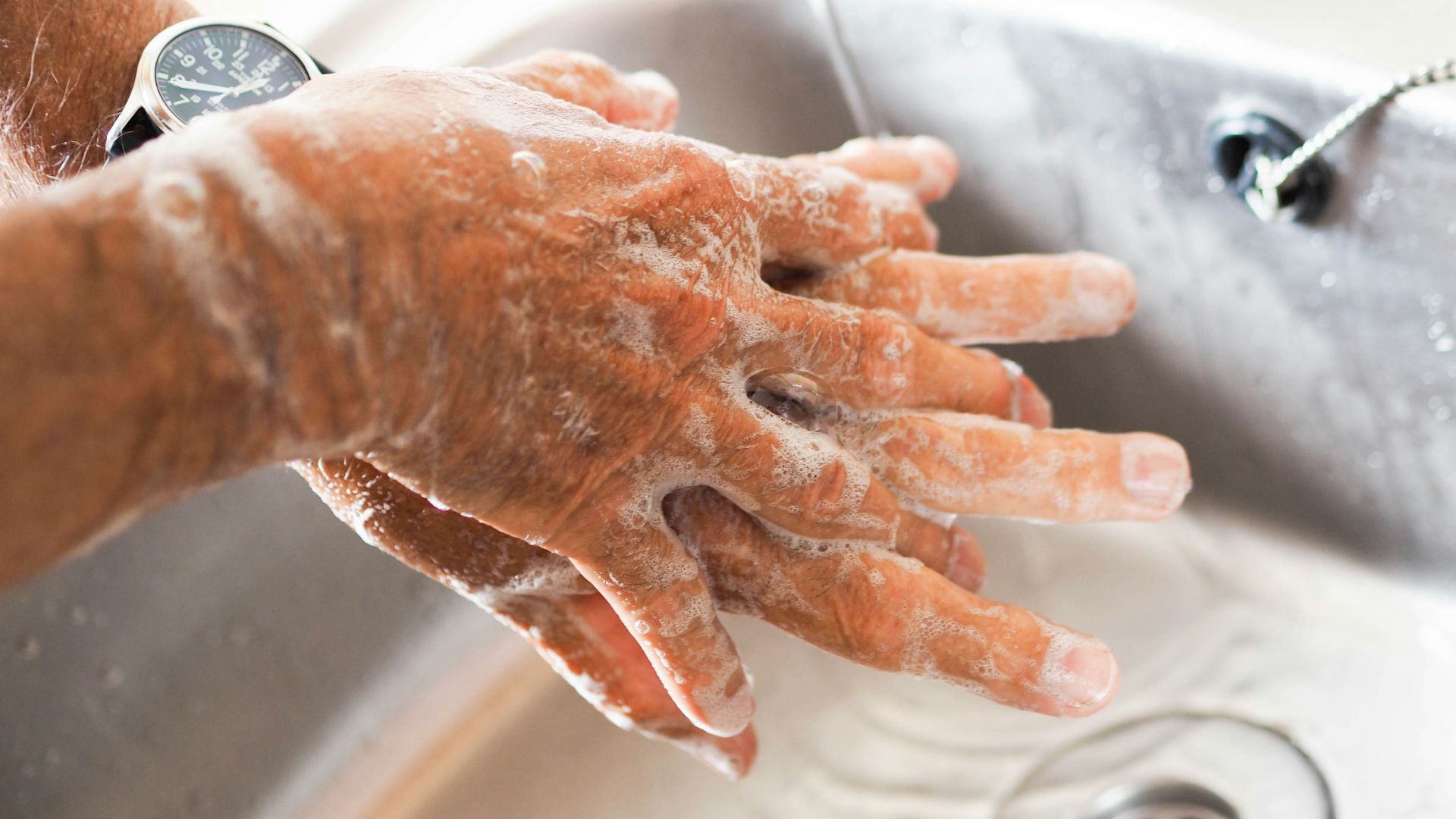 person washing hands on sink