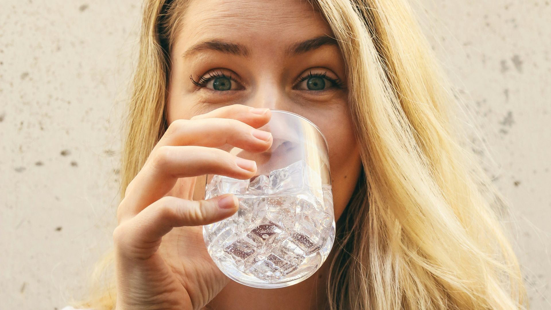 woman in white crew neck shirt drinking water