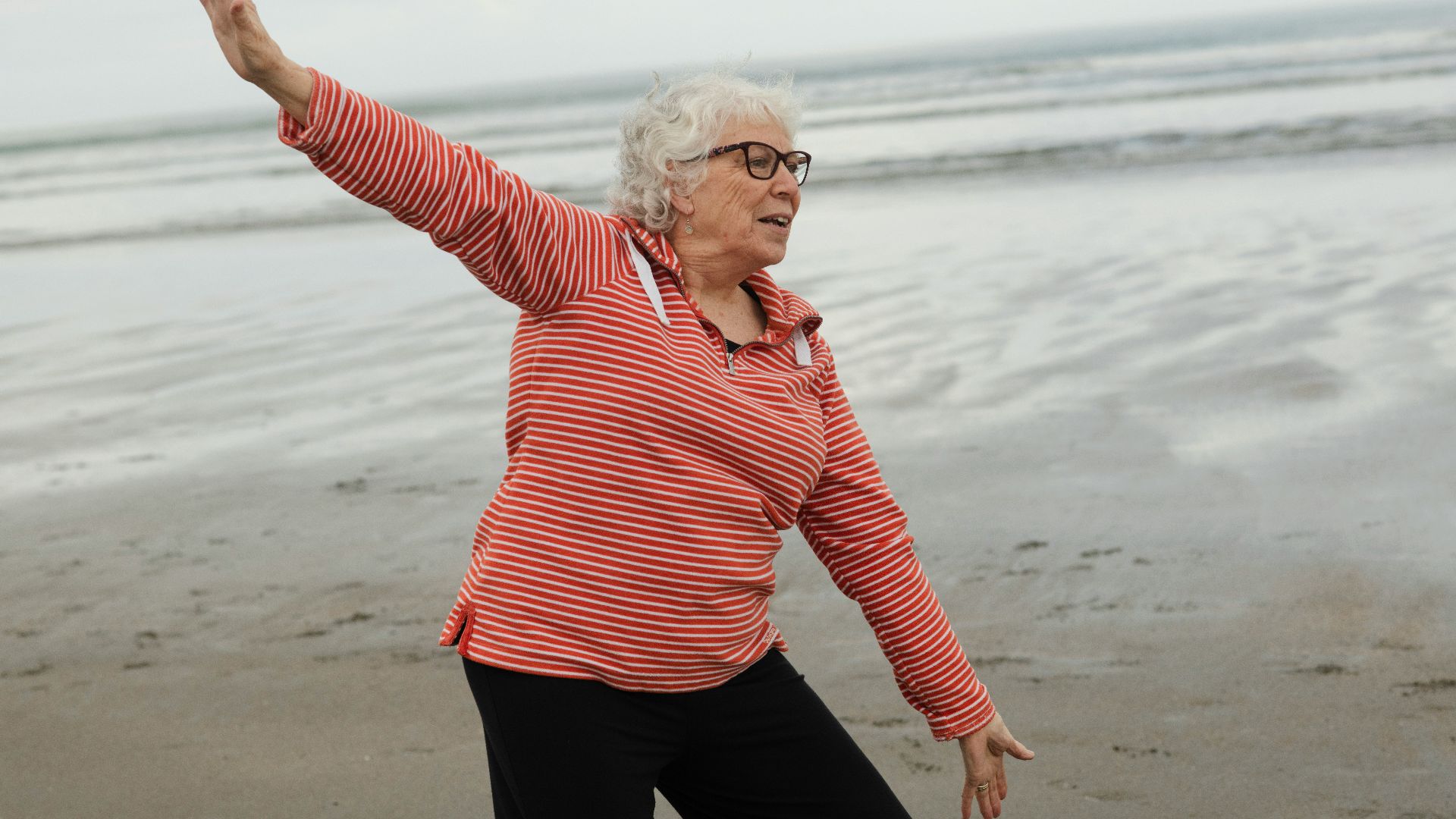 Woman practices tai chi on the beach.