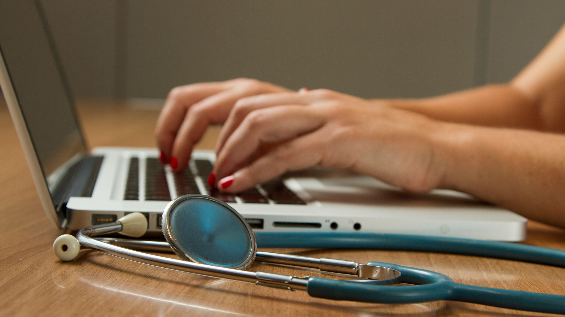 person sitting while using laptop computer and green stethoscope near
