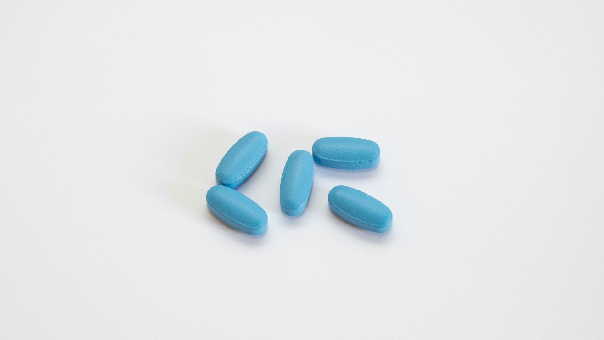 a group of blue pills sitting on top of a white table
